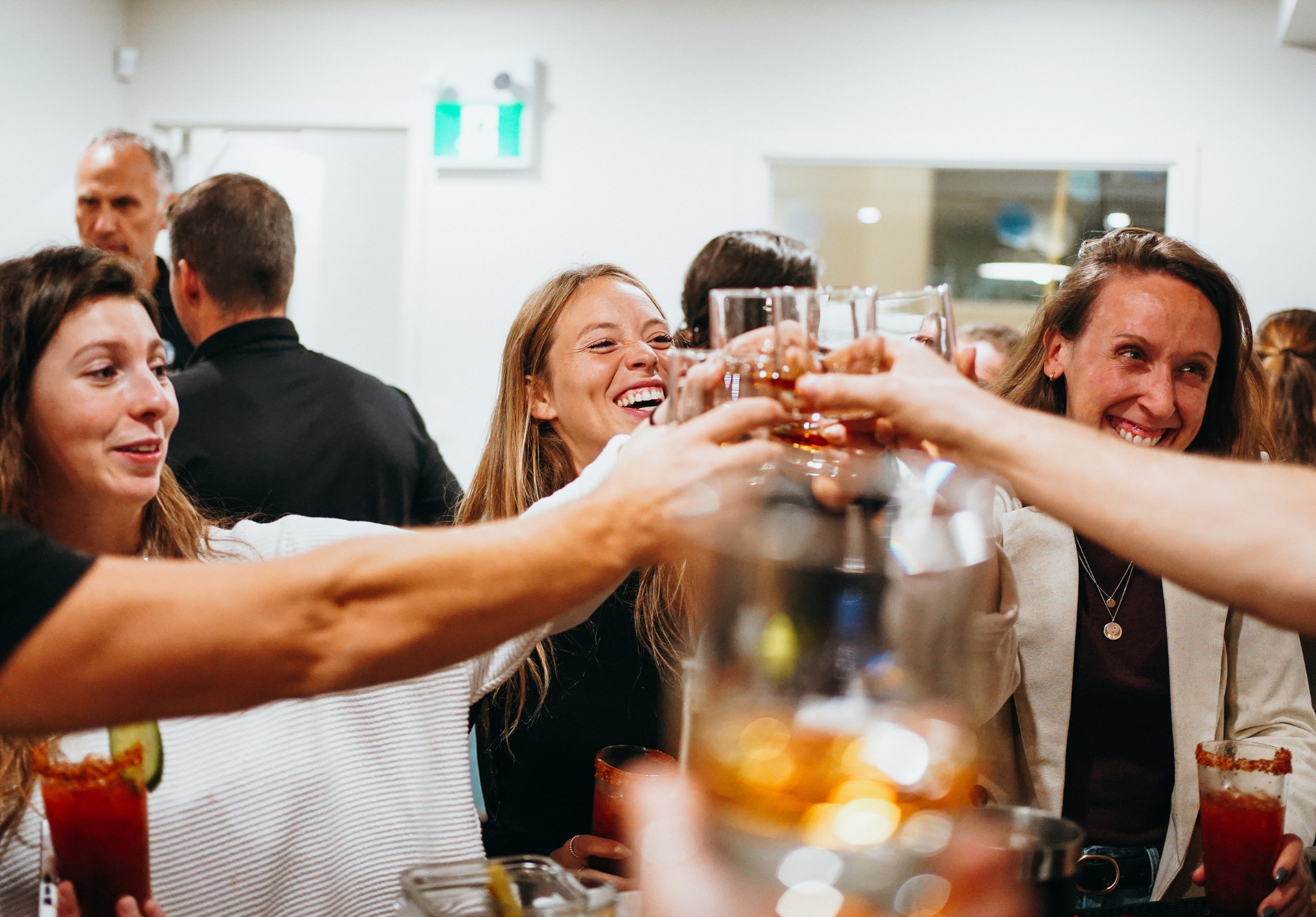 Groupe de personnes souriantes levant leurs verres pour un toast lors d'une fête ou d'une célébration.