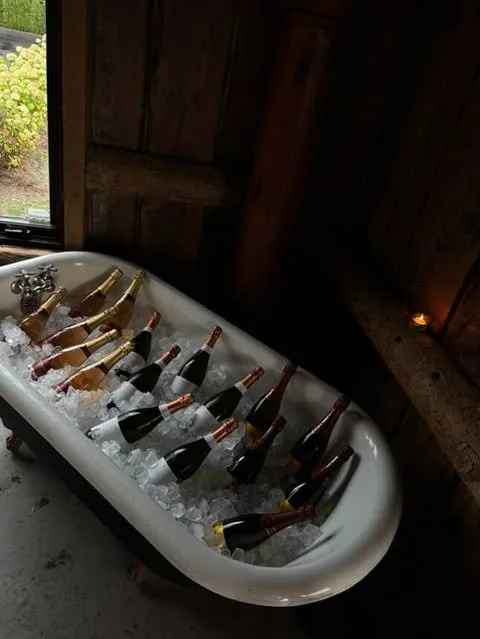 Bain de glace avec plusieurs bouteilles de champagne dans une baignoire en intérieur, bois au mur