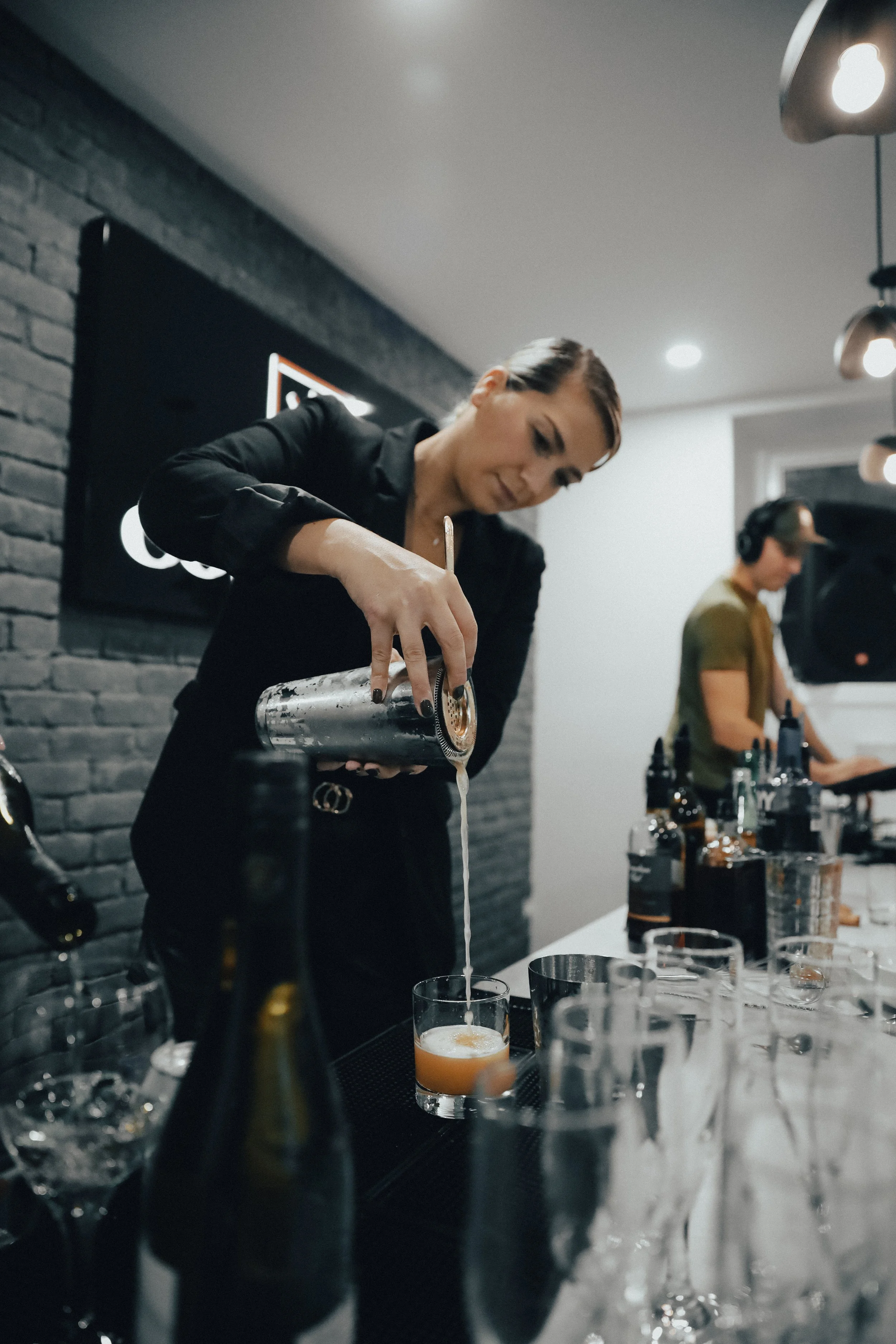 Une femme verse un cocktail dans un verre lors d'un service dans un bar moderne