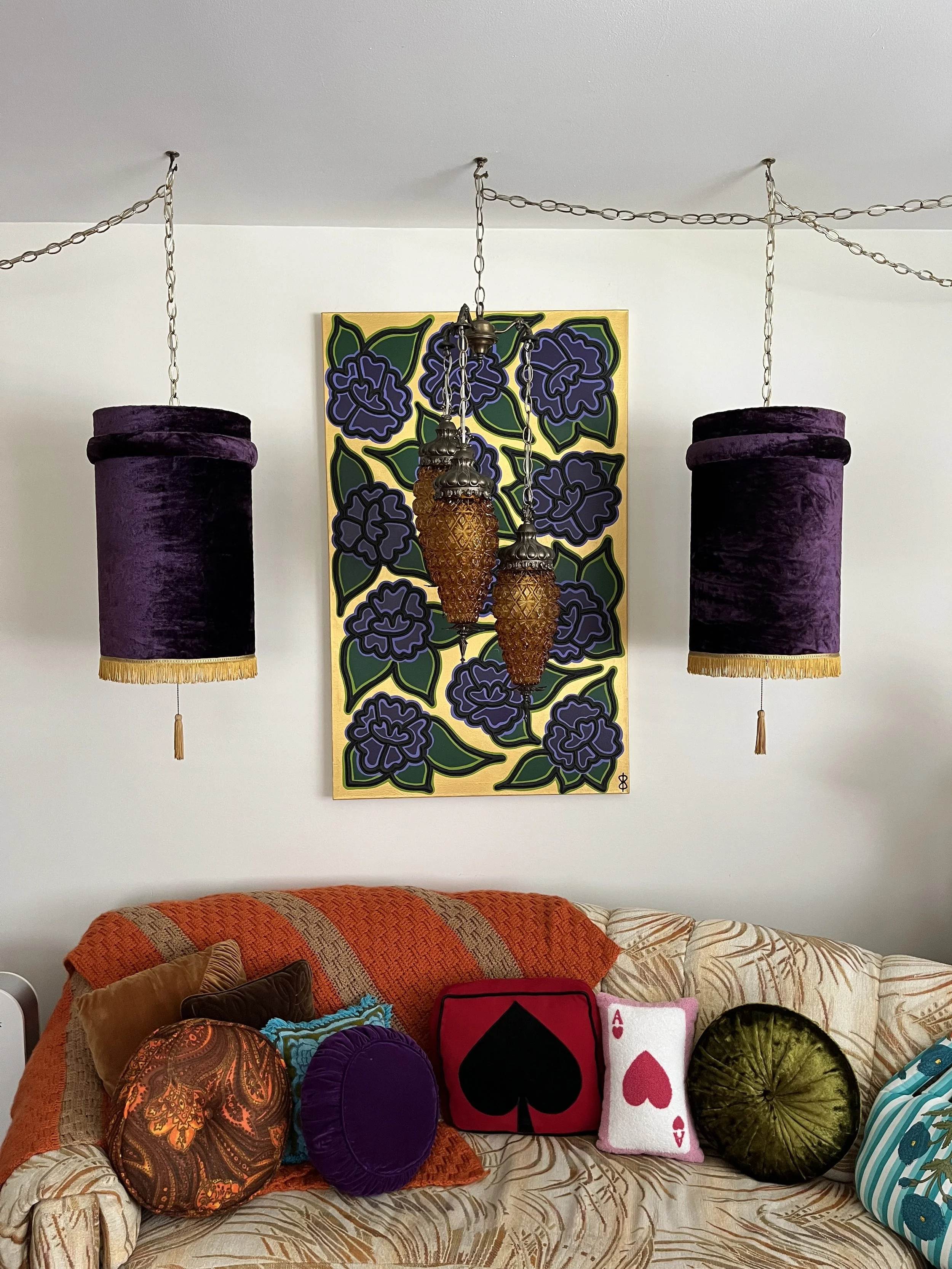 Vintage three-tier hanging lamp displayed above a colorful sofa, surrounded by original artwork by The Eye of Ingrid.