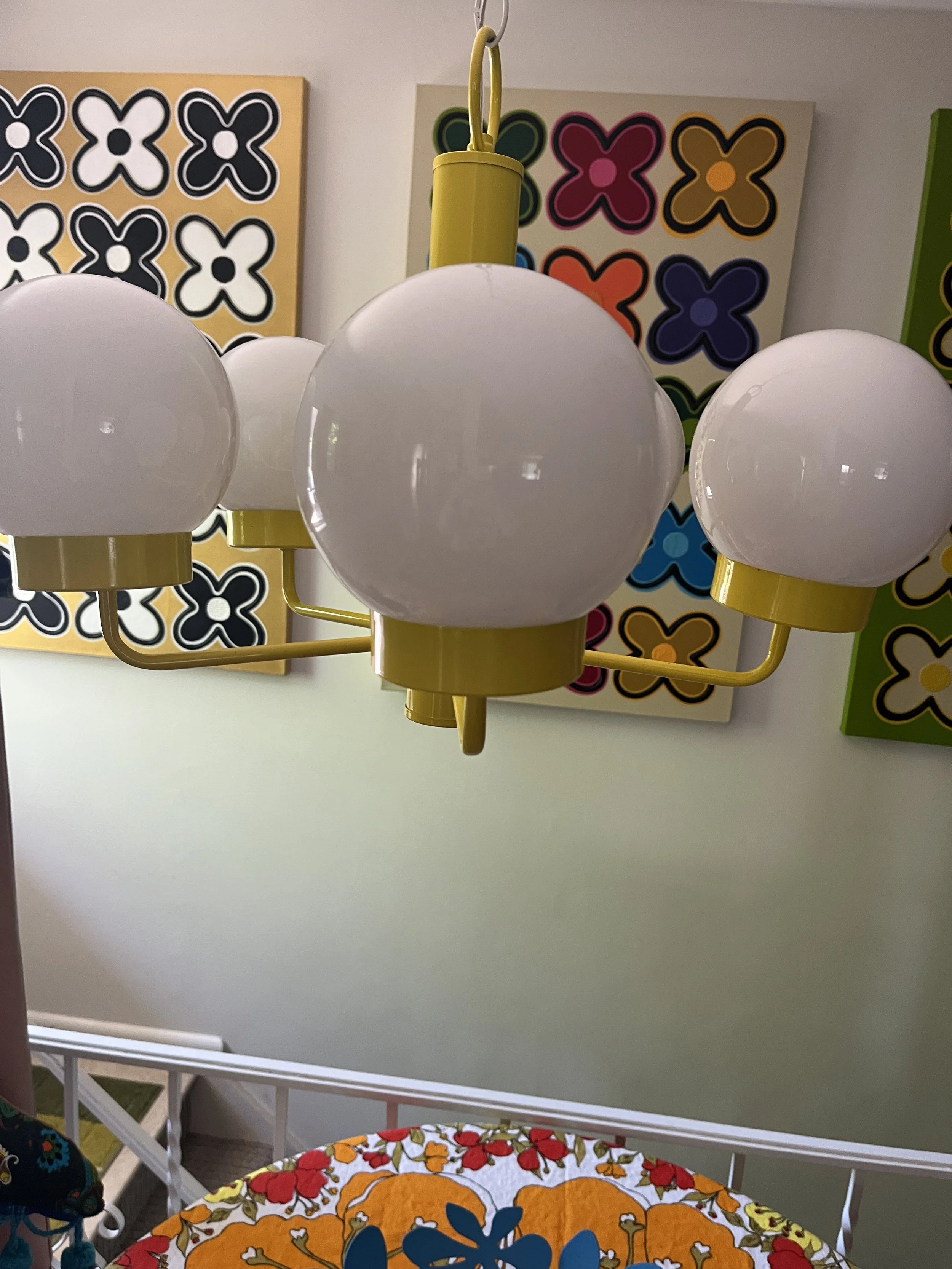 Close-up of glossy white spherical glass globe and canary yellow metal fittings on a restored vintage chandelier.