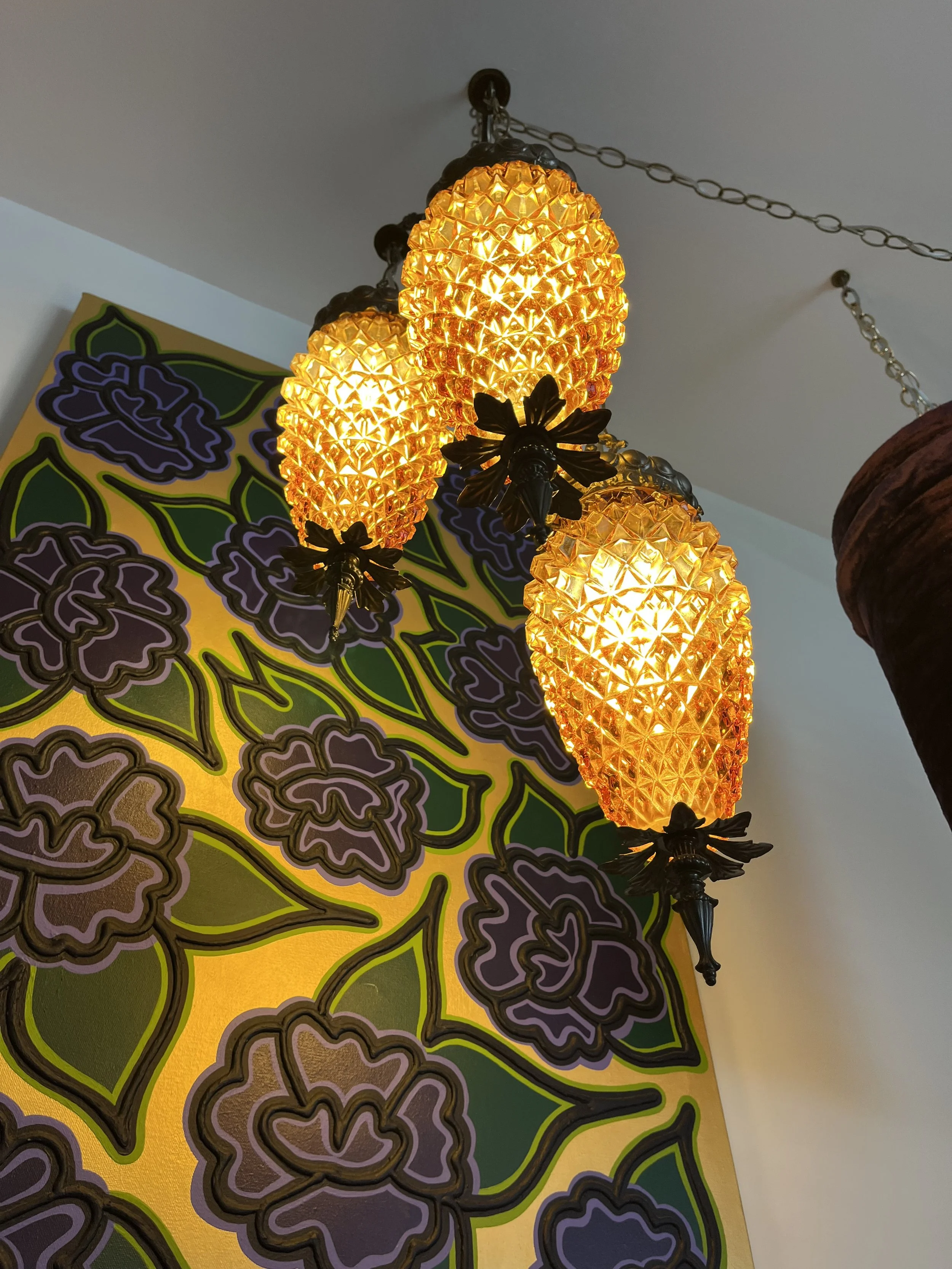 Close-up from below all three illuminated amber glass shades, showing their textured glass and warm glow.