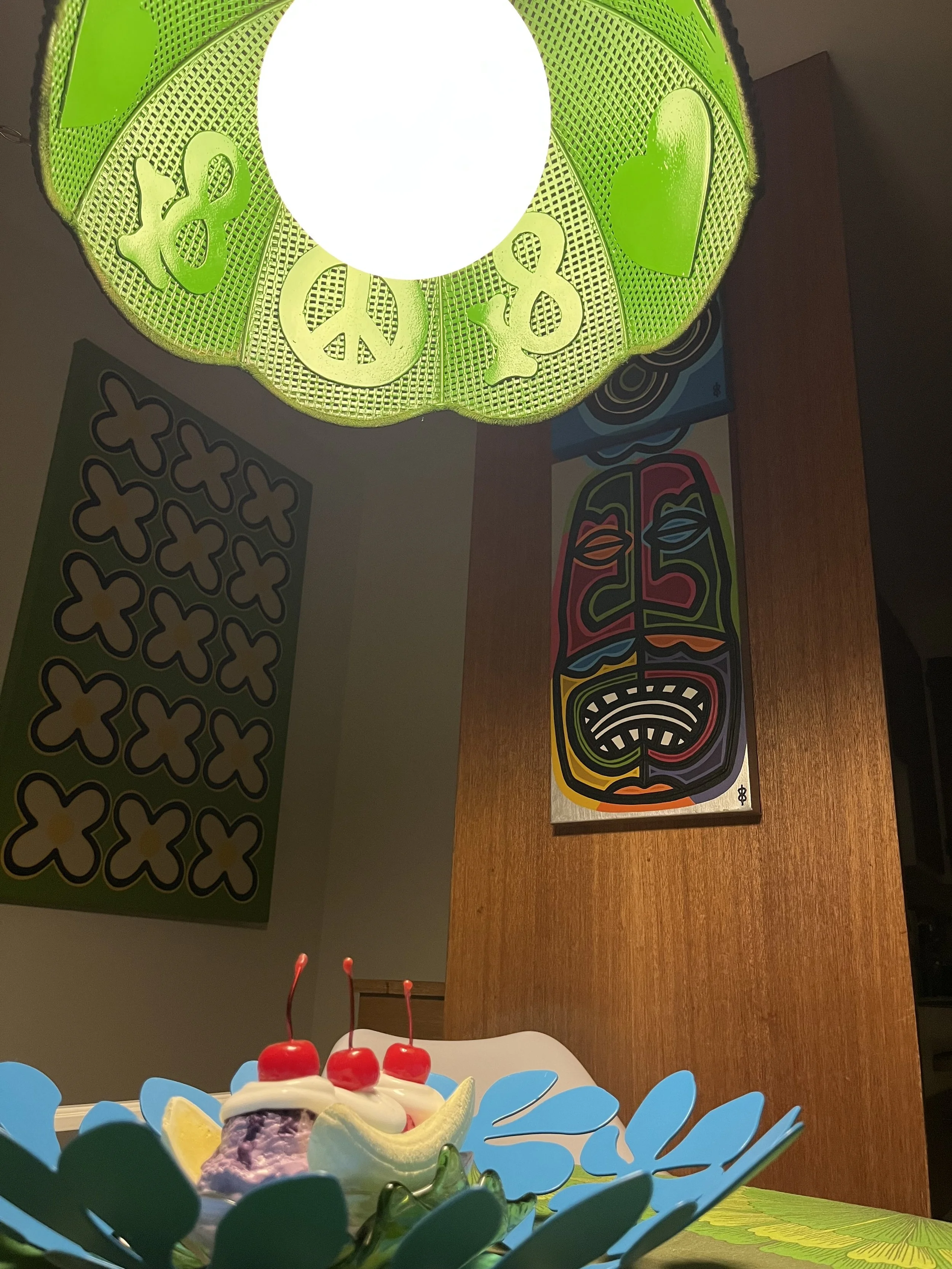 Night view from beneath the Peace & Love hanging light, showing the illuminated acrylic globe casting light through the hand-painted rattan shade.