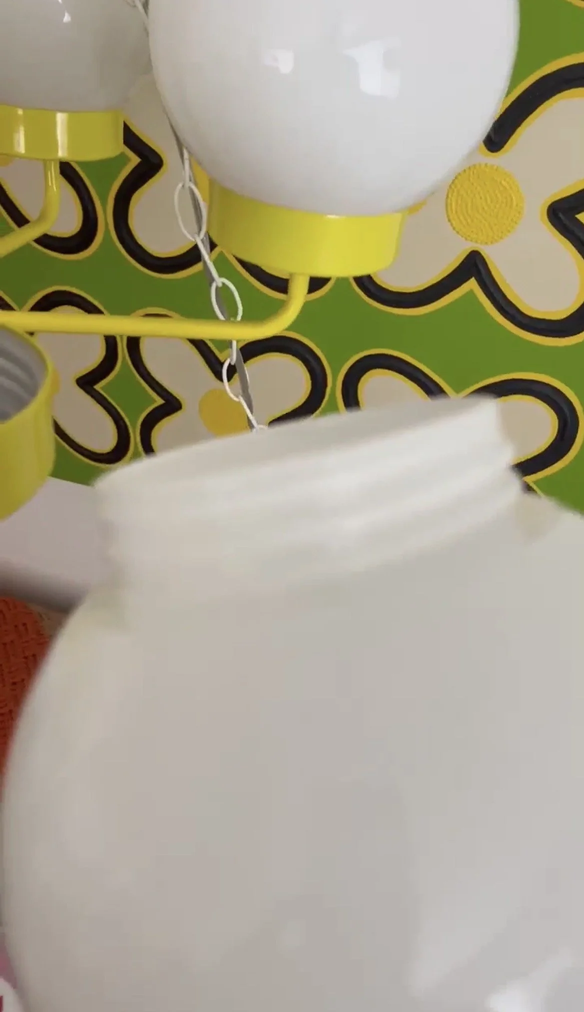 Close-up of white glass globe removed from its metal yellow chandelier fitting, showing the threaded opening used for attachment.