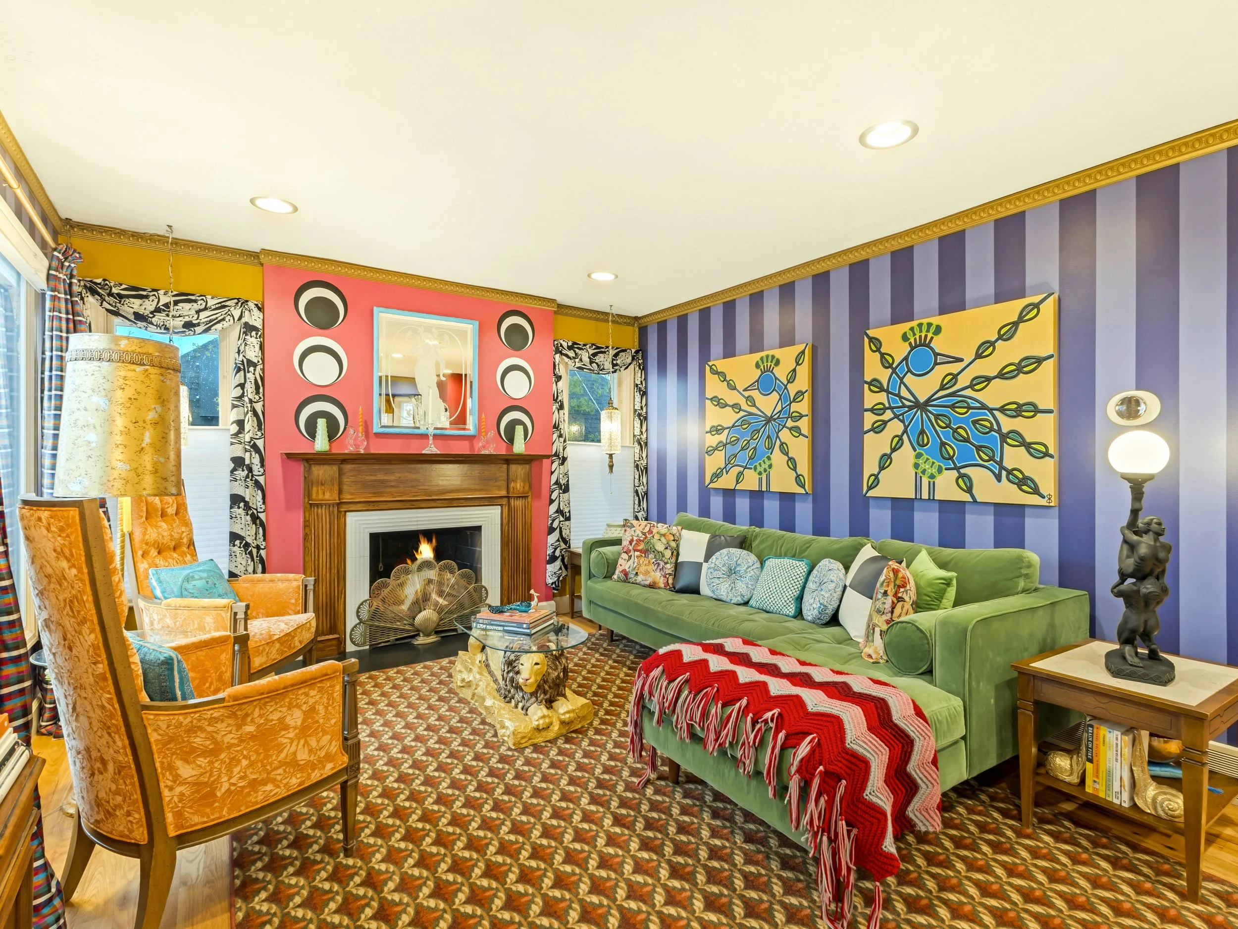 A colorful maximalist living room designed by The Eye of Ingrid, layered with vintage furniture, bold color and pattern, and featuring The Eye of Ingrid's original peacock paintings, "Rare Birds," above a green velvet sofa.