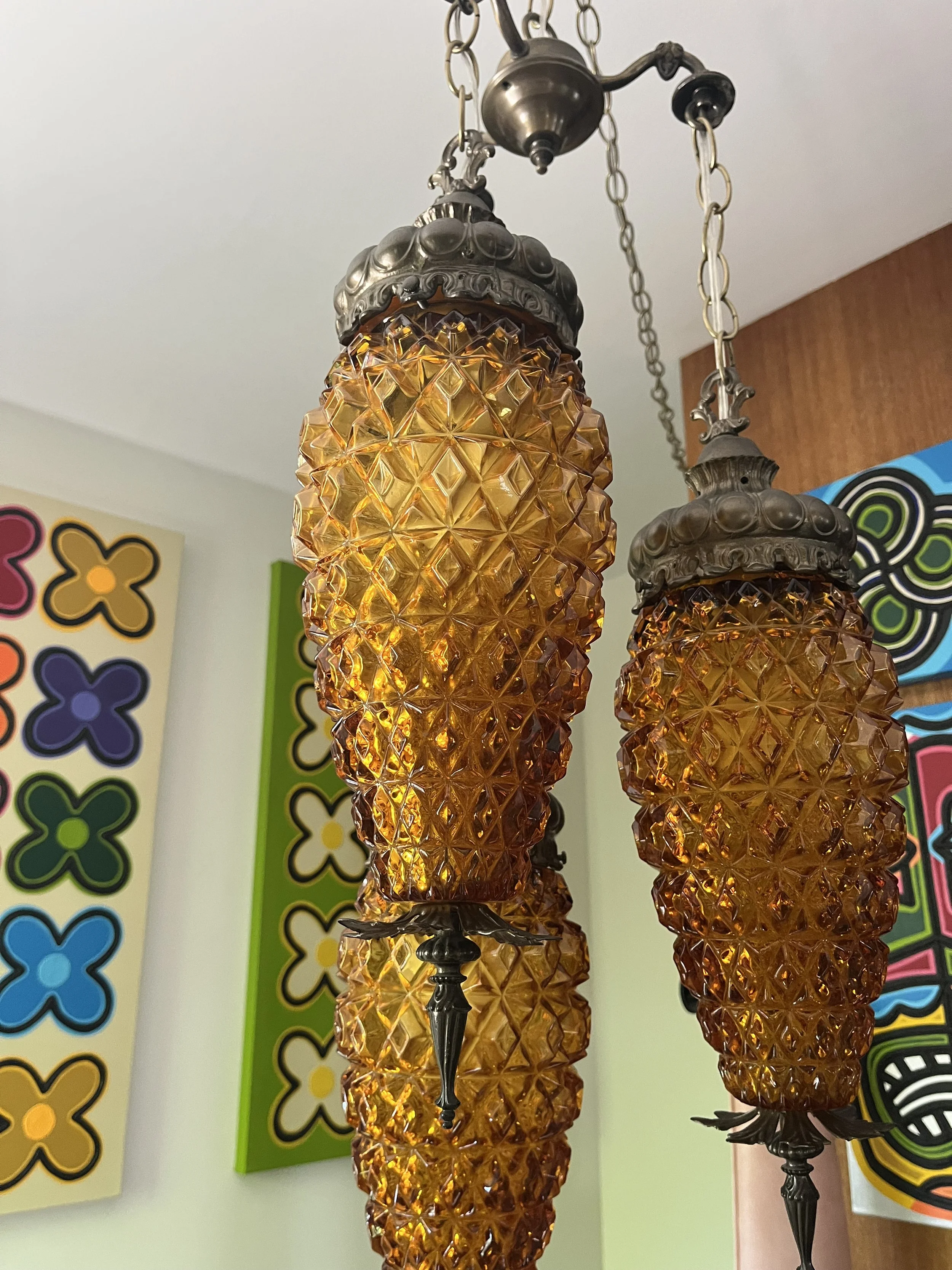 Close-up of the vintage three-tier hanging lamp, showing the textured amber glass shades and ornate cast metal fititngs.