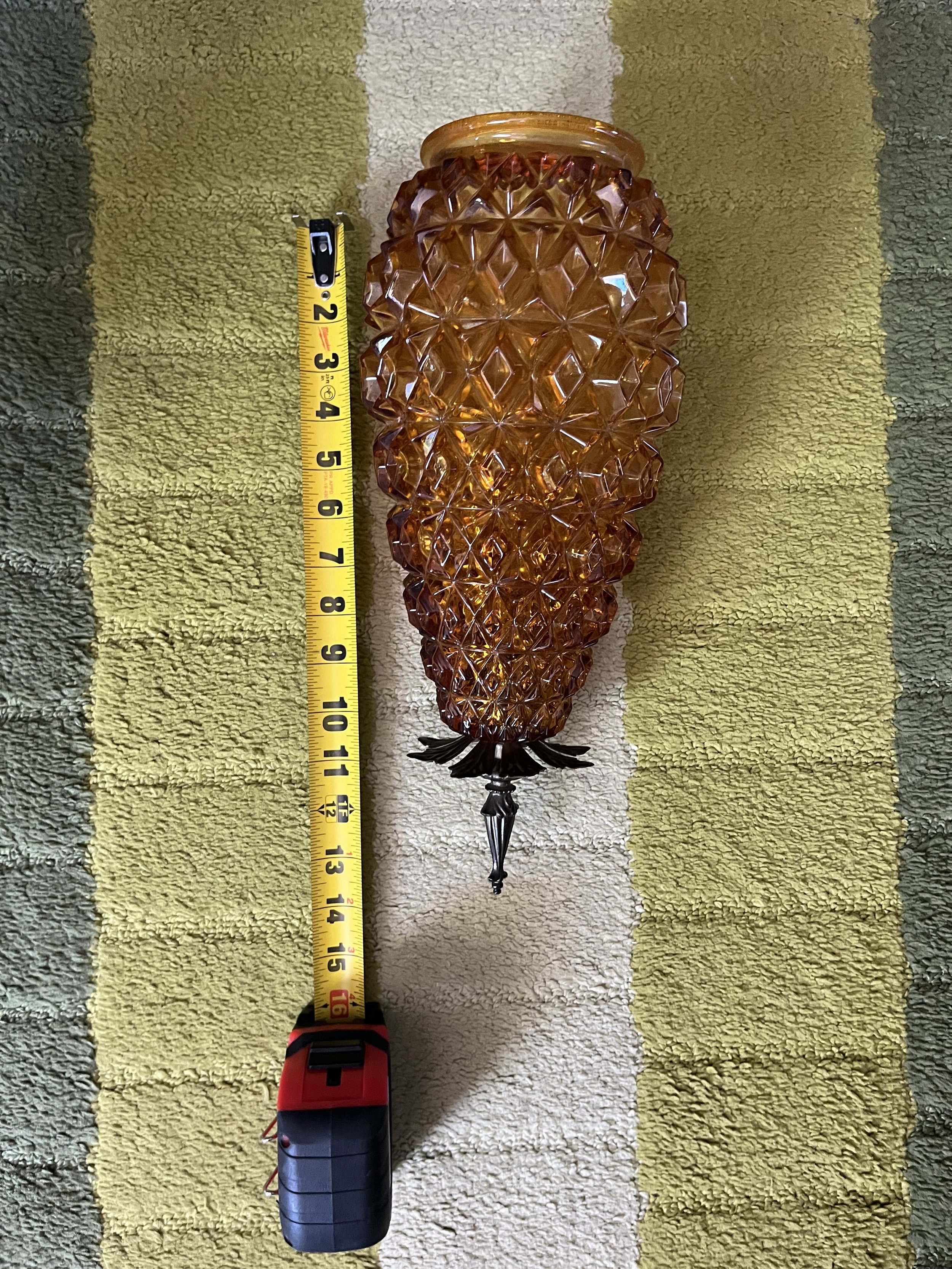 SIngle amber glass shade shown beside a measuring tape to document its size and proportions.