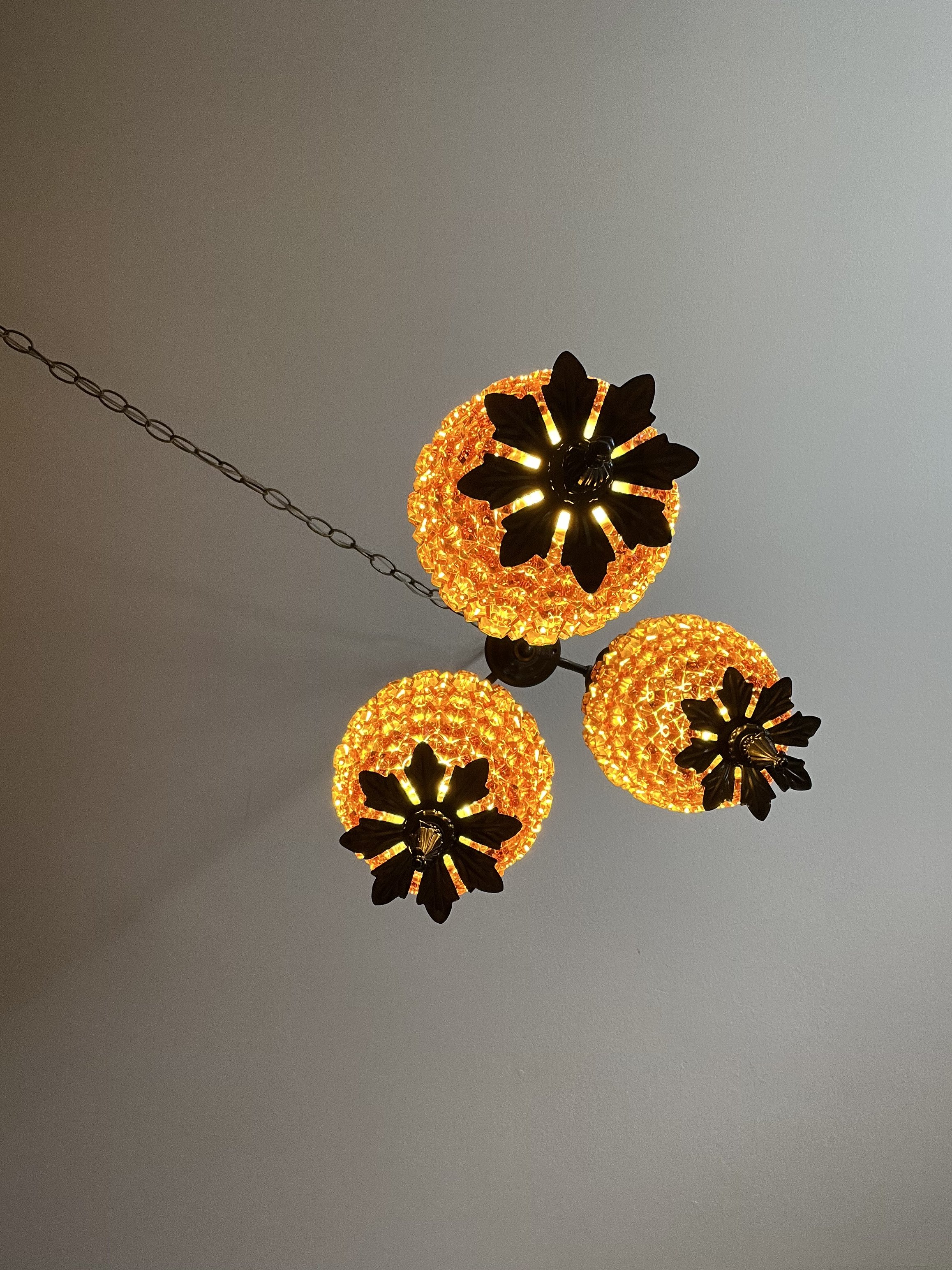 Underside view of the illuminated three-tier hanging lamp, showing the warm amber light through all three textured glass shades.