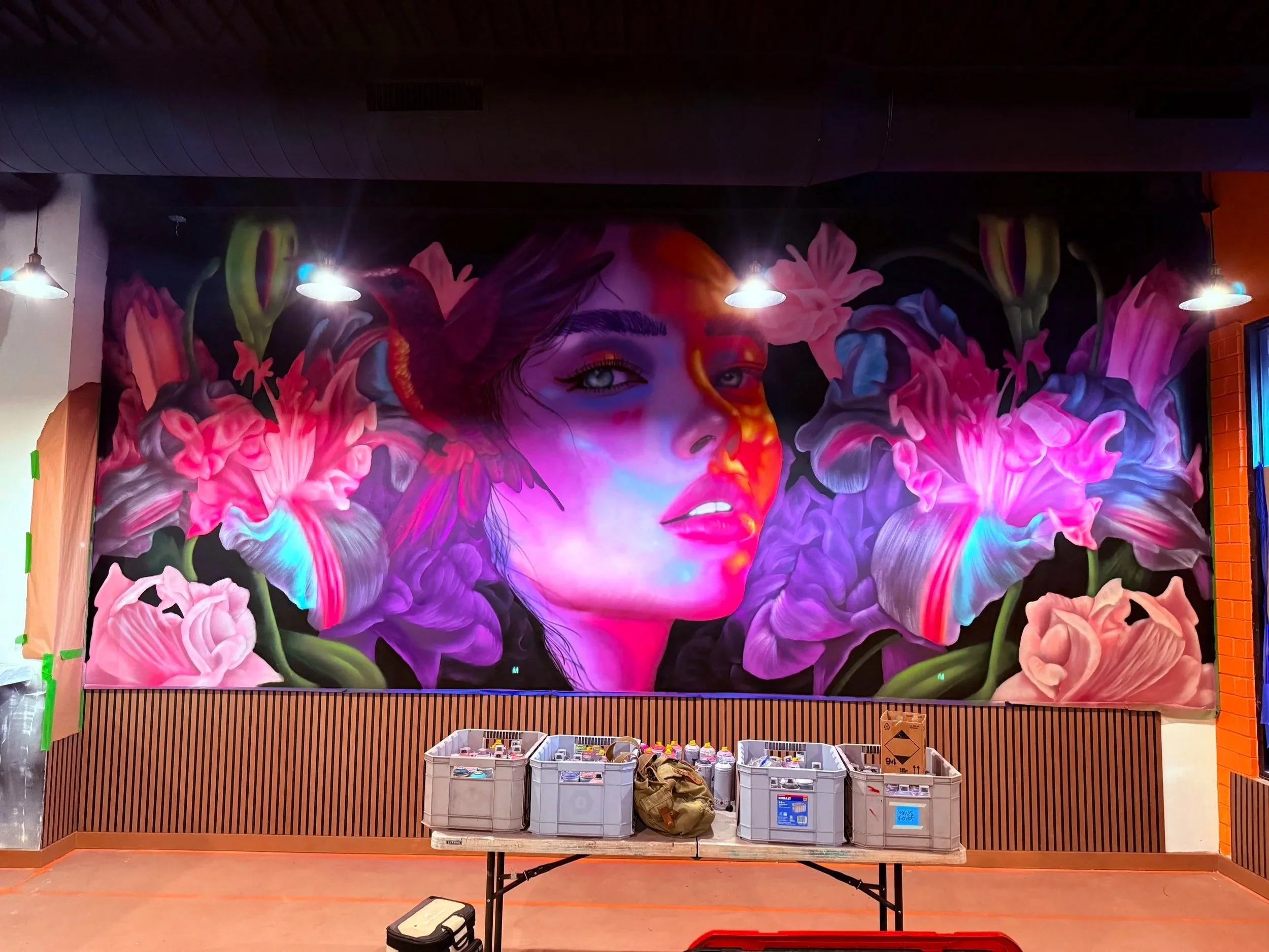 Colorful mural of a woman's face surrounded by pink flowers