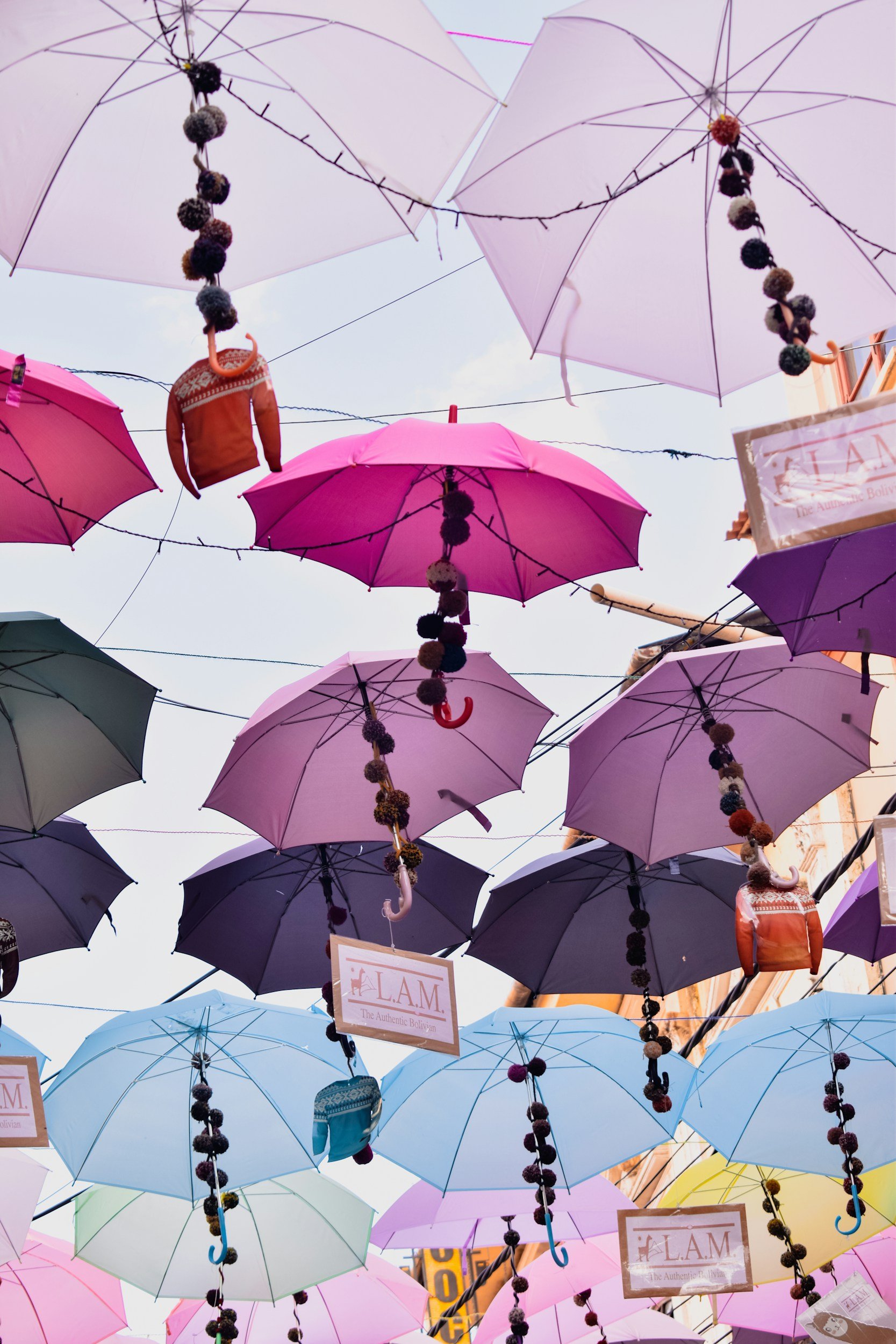 Colorful umbrellas and decorative items hanging in a market setting against the sky.