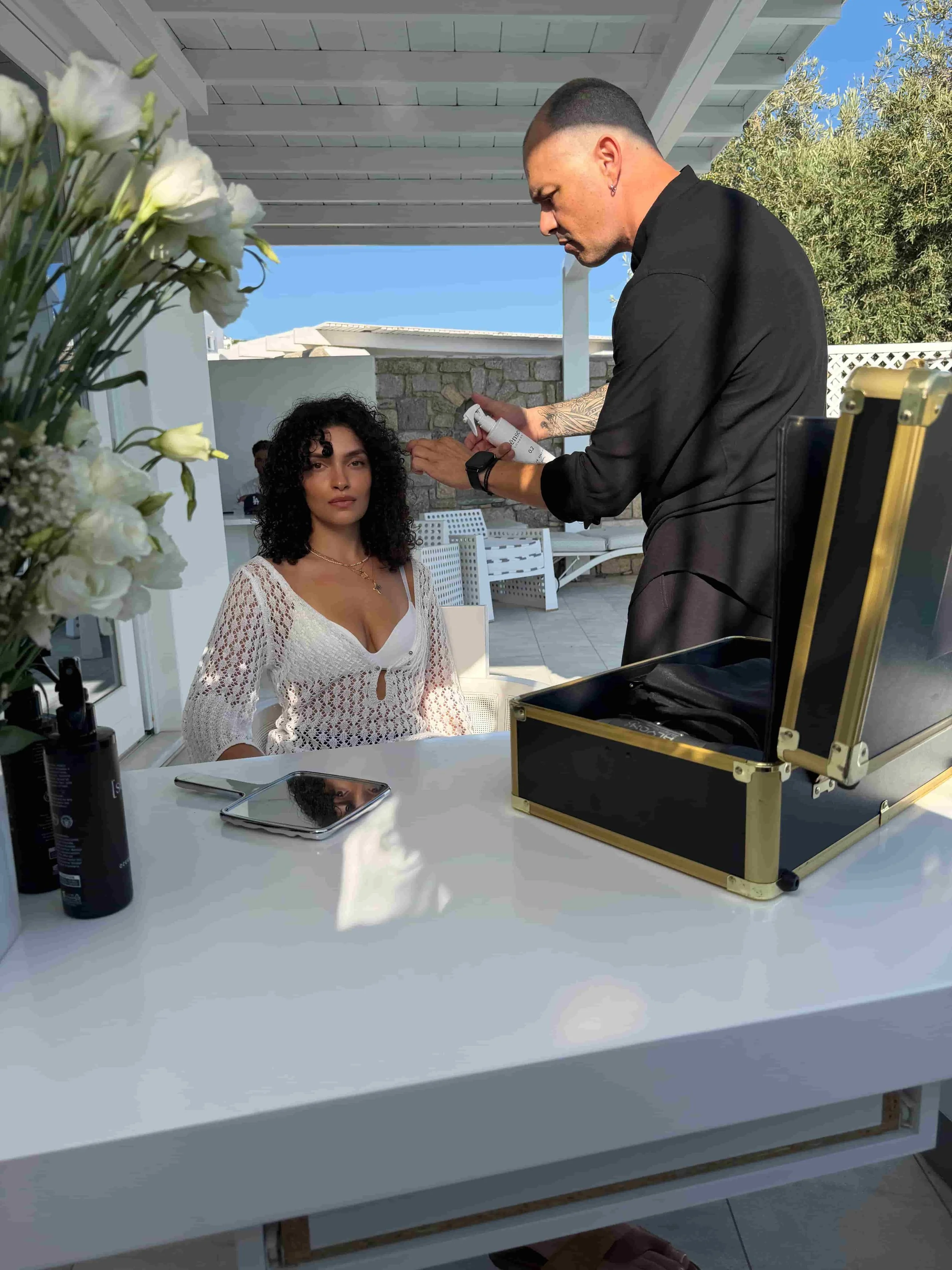 A hairstyling artist is using a hair product in Athens to style a bride's hair - femme by [sēnsei]