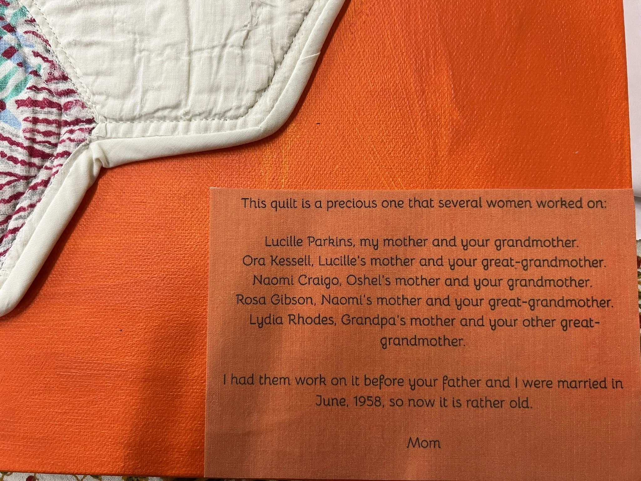 A quilt with a handwritten note attached, describing the people who worked on it and their relationships.