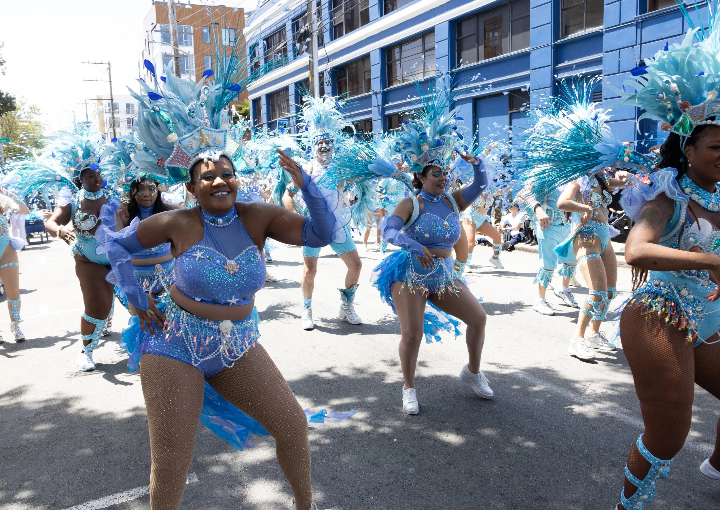 Dancers in blue water-themed costumes dancing in the street at the 2025 San Francisco Carnaval parade