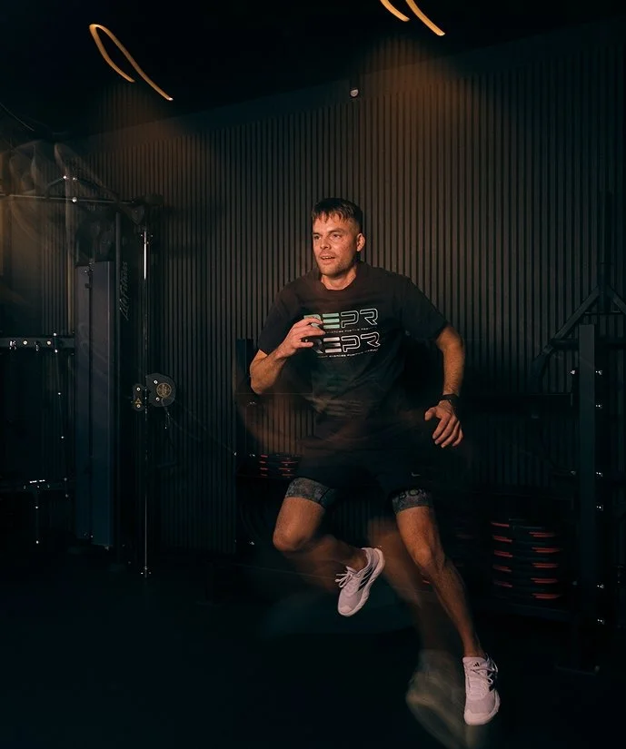 Man som tränar på ett gym i en mörk lokal, gör en snabb rörelse eller hopp.