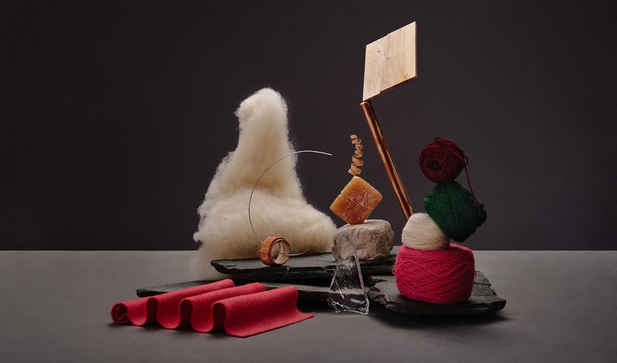 Konstnärlig arrangemang av garn, stenar, metall och trä på en mörk bakgrund.