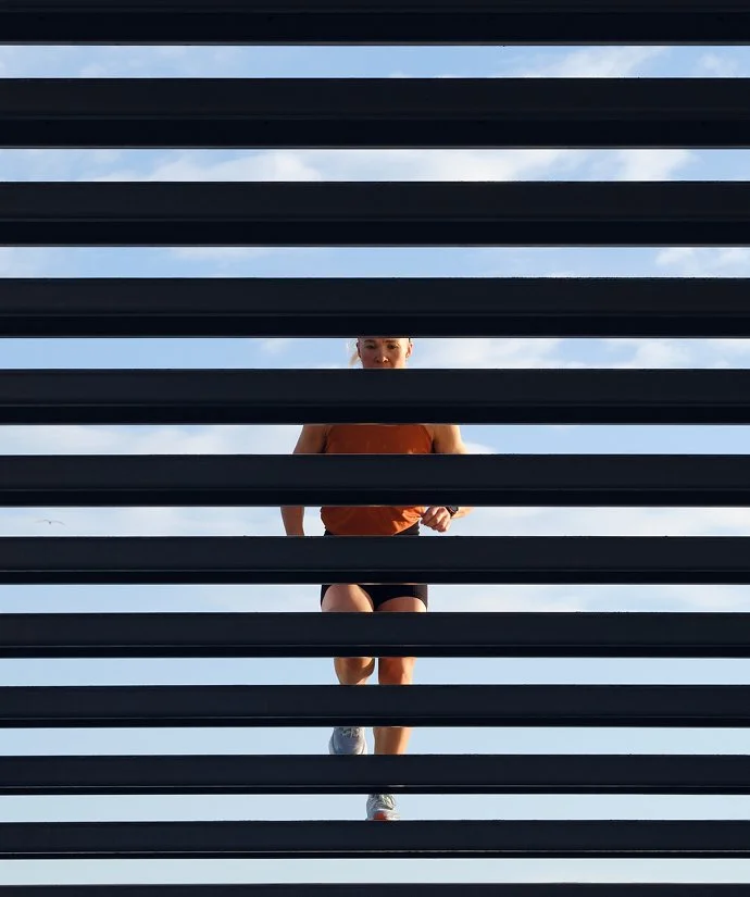 Person som springer utomhus bakom en glas- och metallfönsterjalusi.