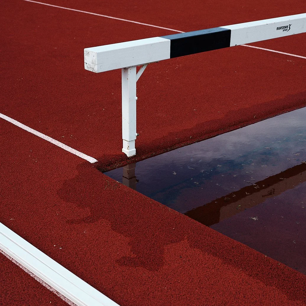 En röd sportarena med ett hinder och en vattenpöl.