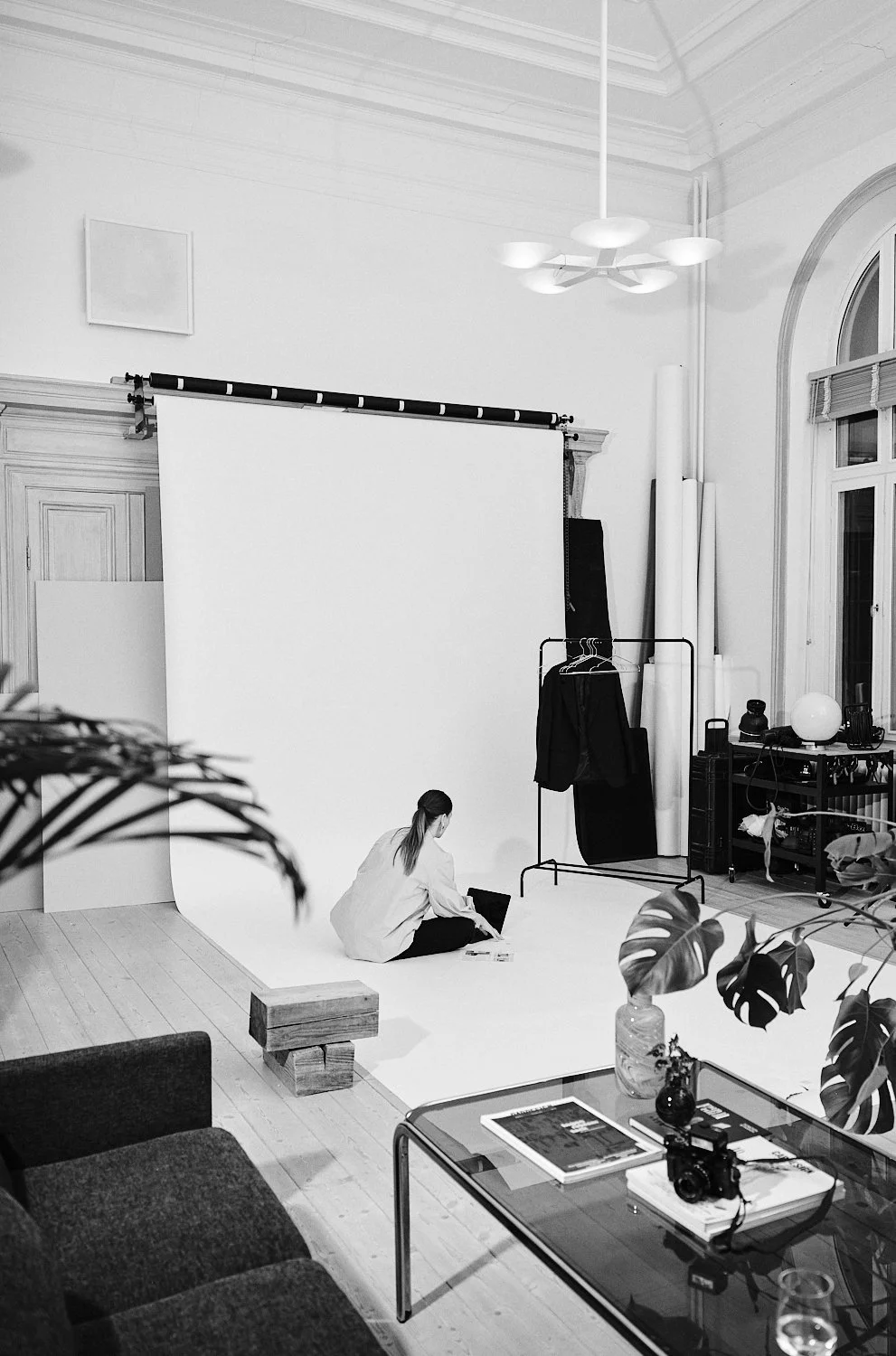 En person sätter upp fotograferingsmaterial i en studio med vit bakgrund, inredning och teknik.