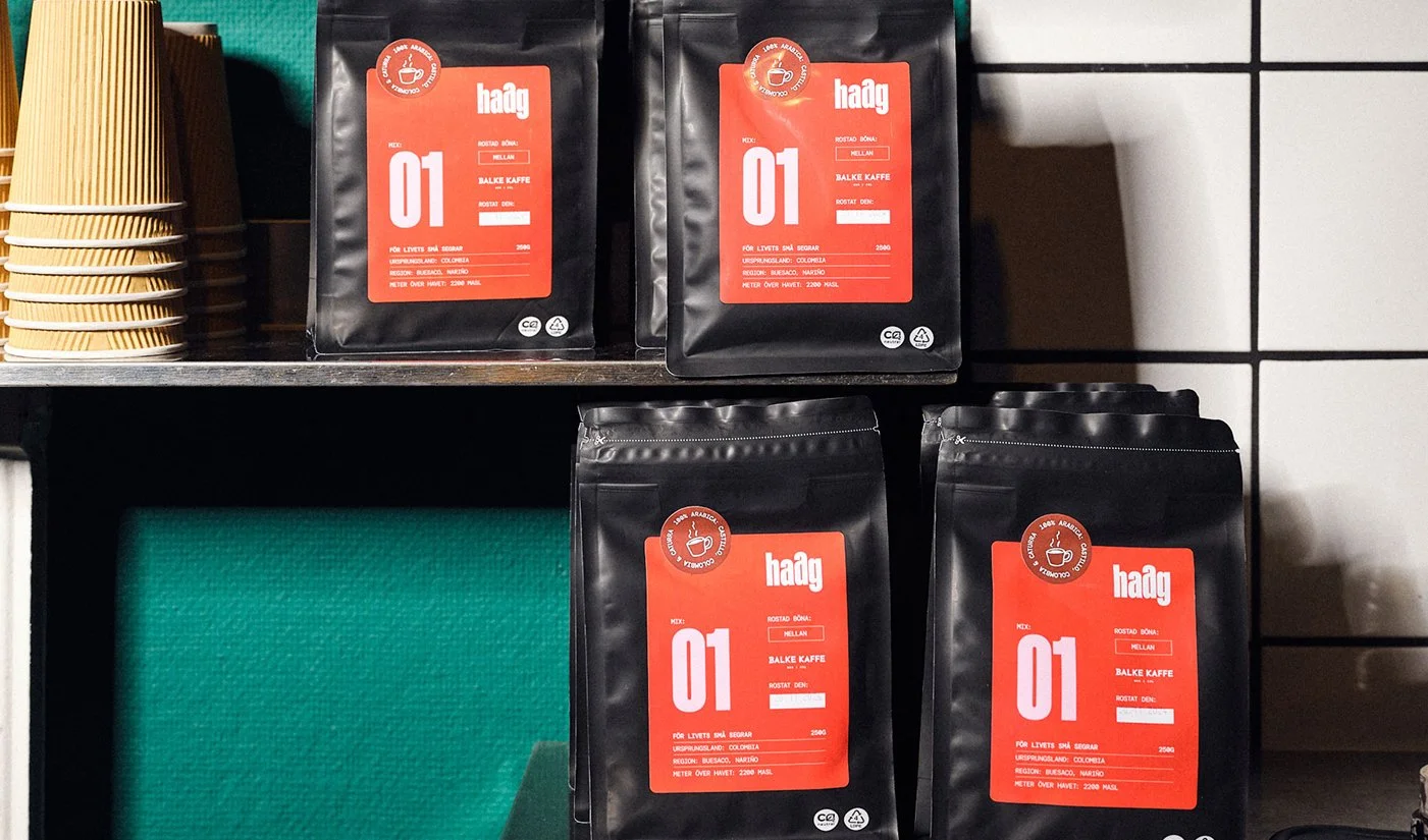 Förpackningar av kaffesorter på hylla, märkta med 'Haag' och '01', i butik.