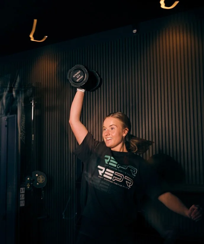 En kvinna som lyfter en hantel i ett gym.