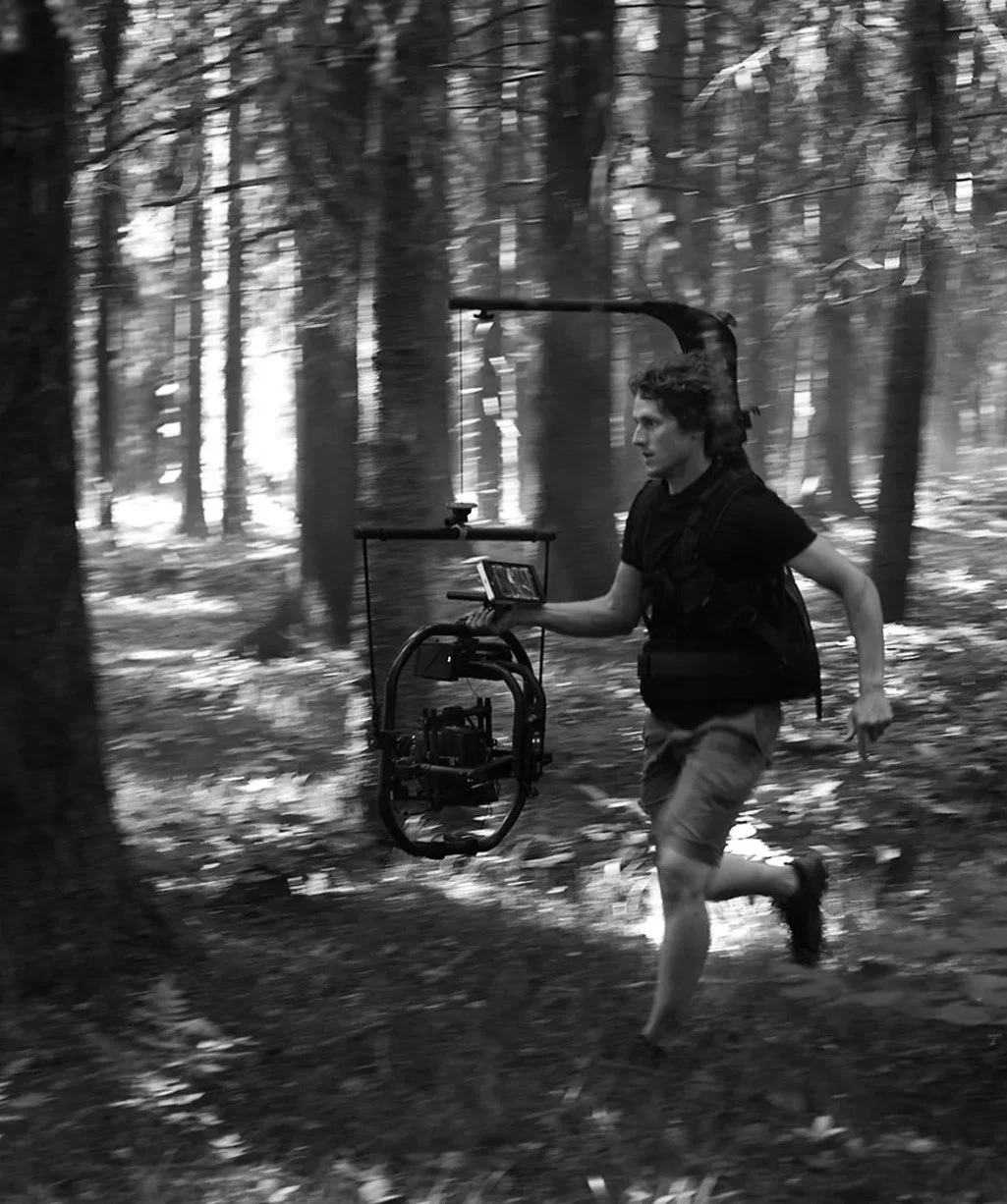 En man springer genom en skog med en filmkamera utrustad för bärbar filminspelning.