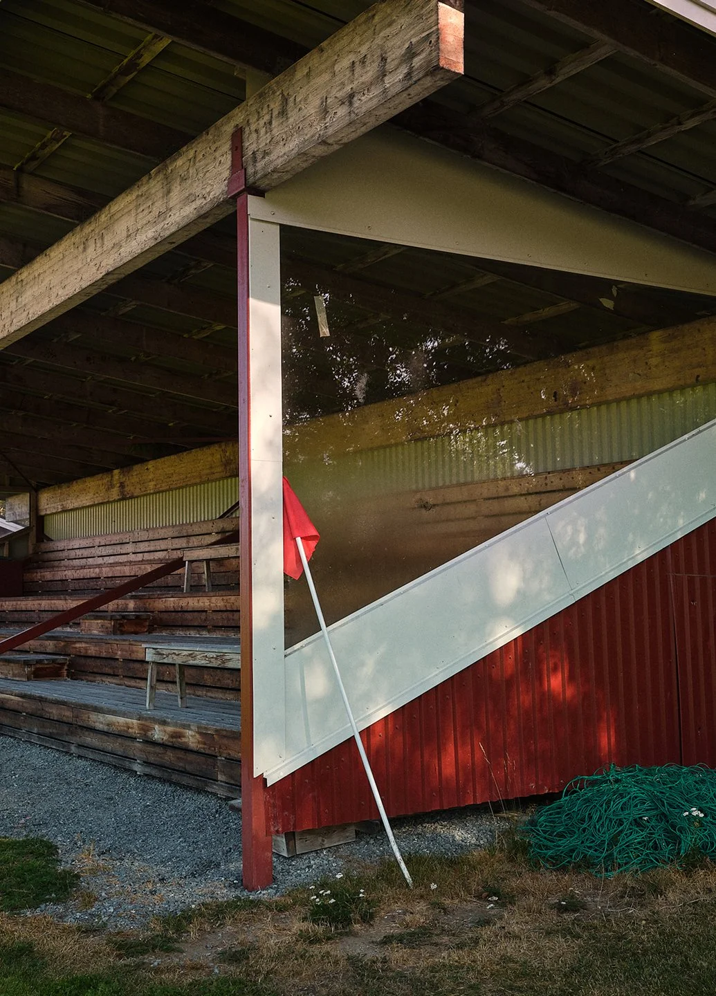 En trappa inomhus med trästeg och en glasvägg. En röd flagga är placerad i marken intill glasväggen.