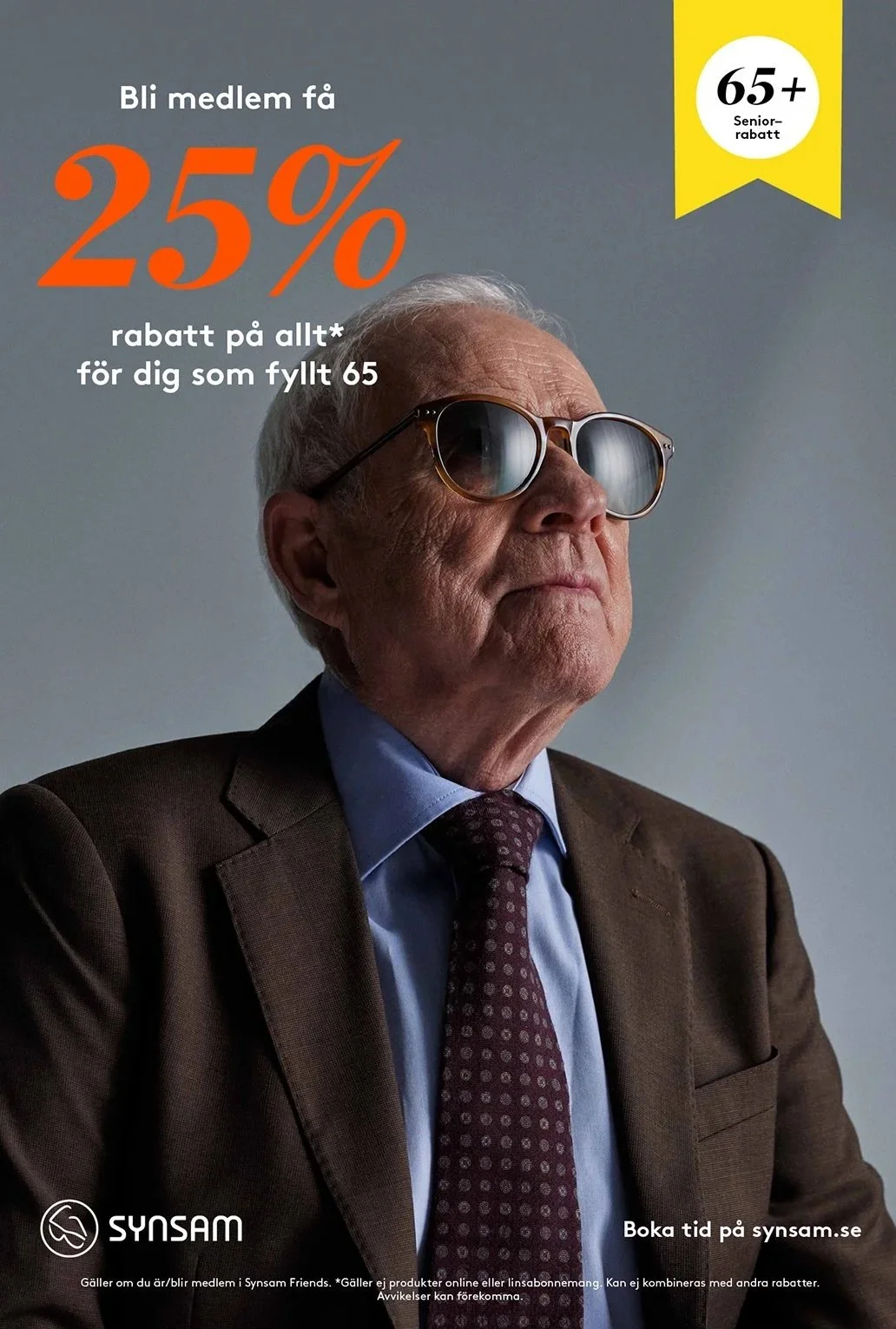 Äldre man i mörk kostym och slips, bär solglasögon, ser seriös ut.