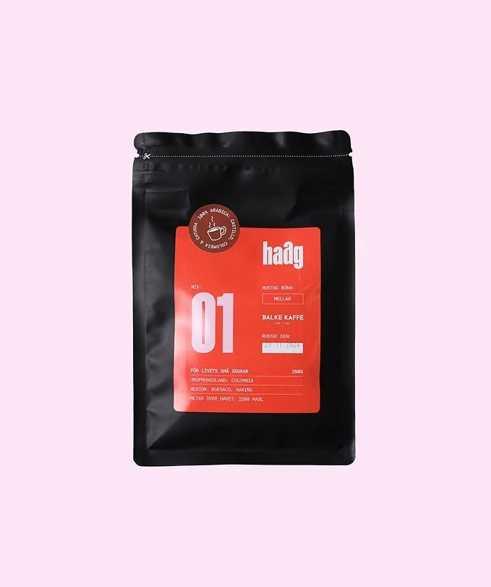En svart kaffepåse med röd etikett som visar att det är balke kaffe, importerad från Colombia, med ett rostningsdatum. Påsen står på en rosa bakgrund.