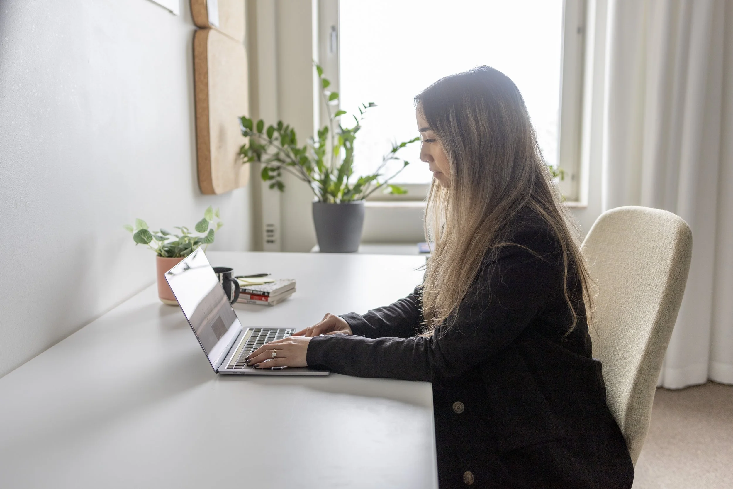 Kvinna sitter vid skrivbord och arbetar på laptop