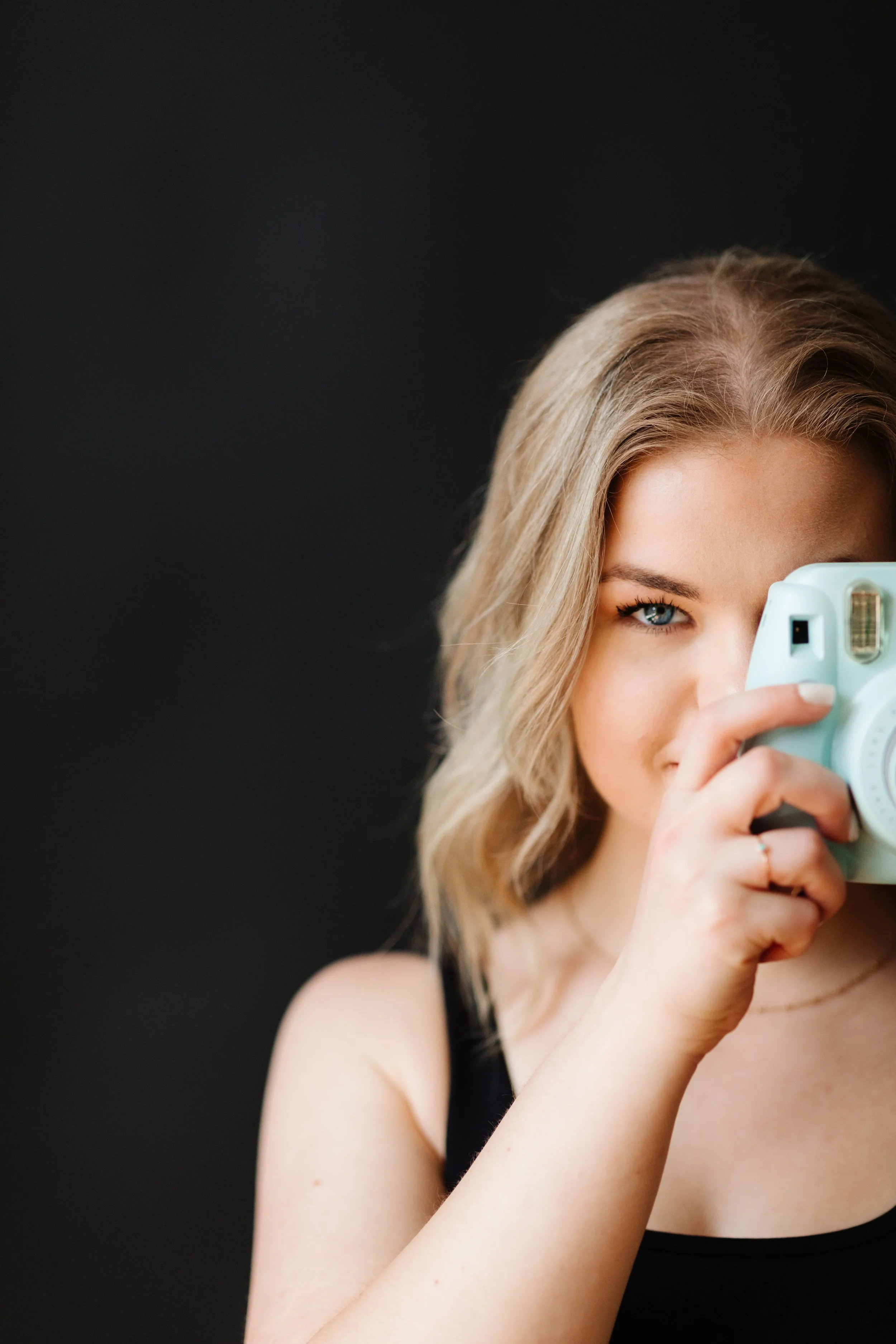 Woman holding a polaroid camera up to her eye