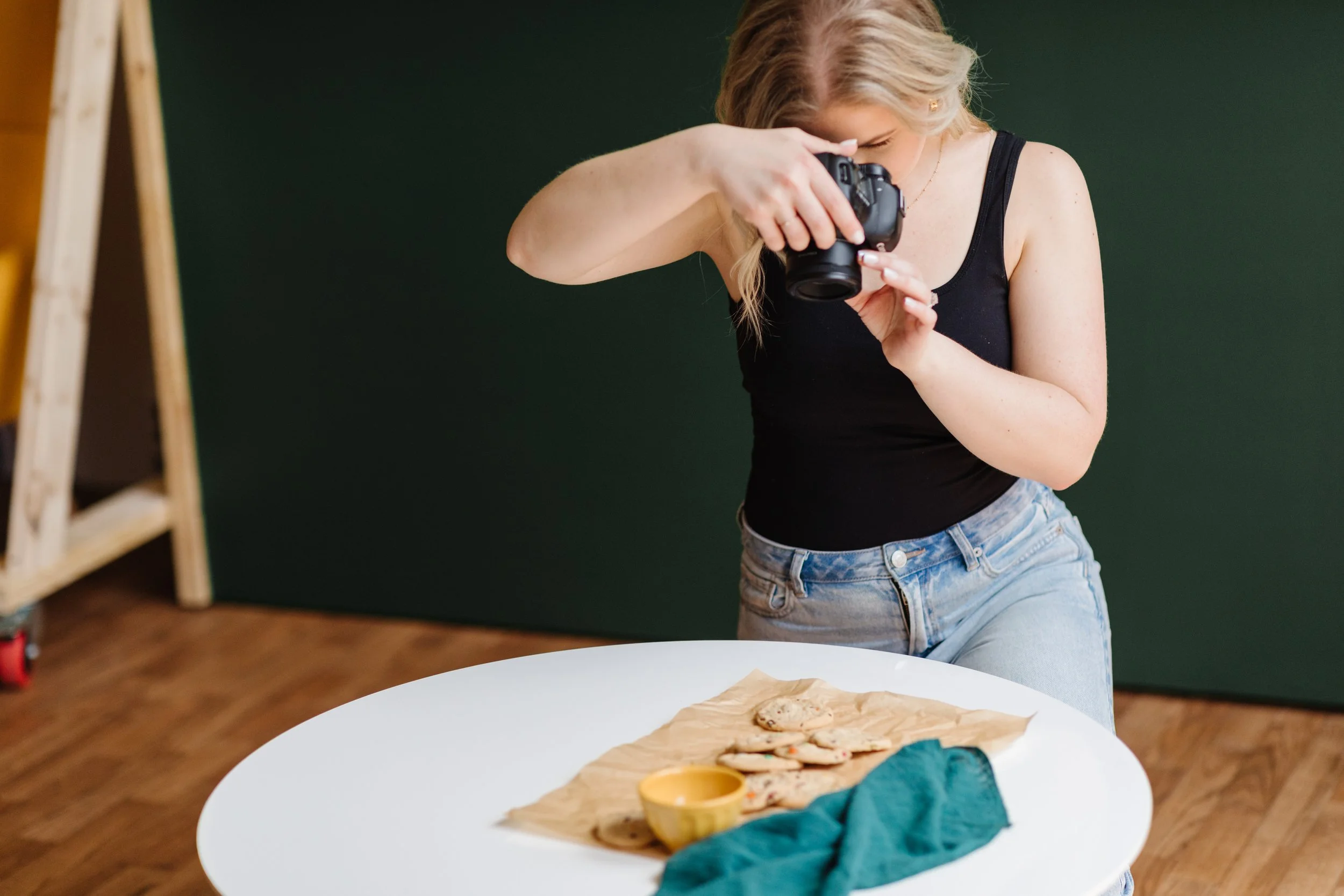 Audrey, food photographer at AM Knizek Photo, taking photos of cookies on a white table