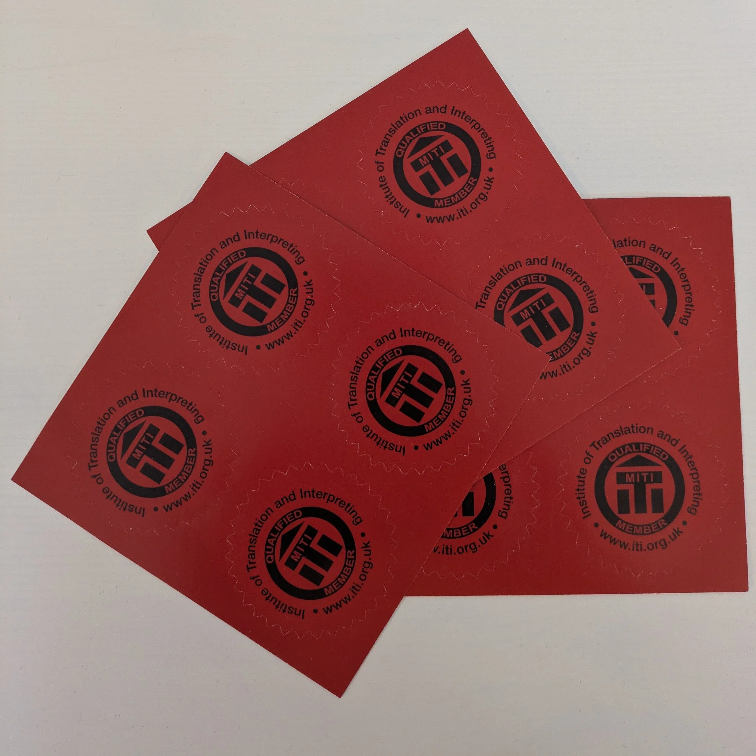 A set of MITI seals. Red stickers with the ITI logo and the following text: Qualified Member. MITI. Institute of Translation and Interpreting. www.iti.org.uk.