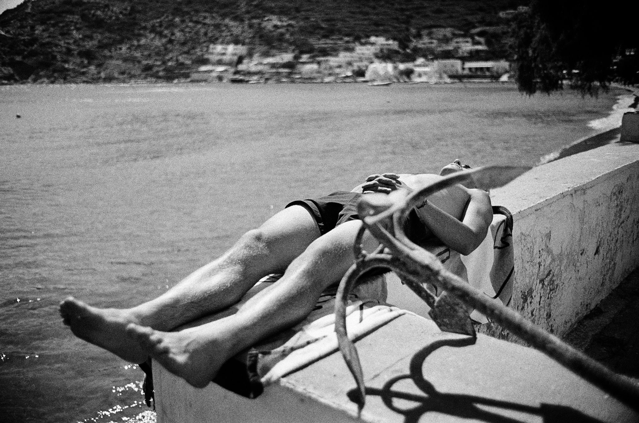 Travel brand photography by New York commercial photographer Adam Lerner - a black and white photo of a young man tanning by the sea in greece