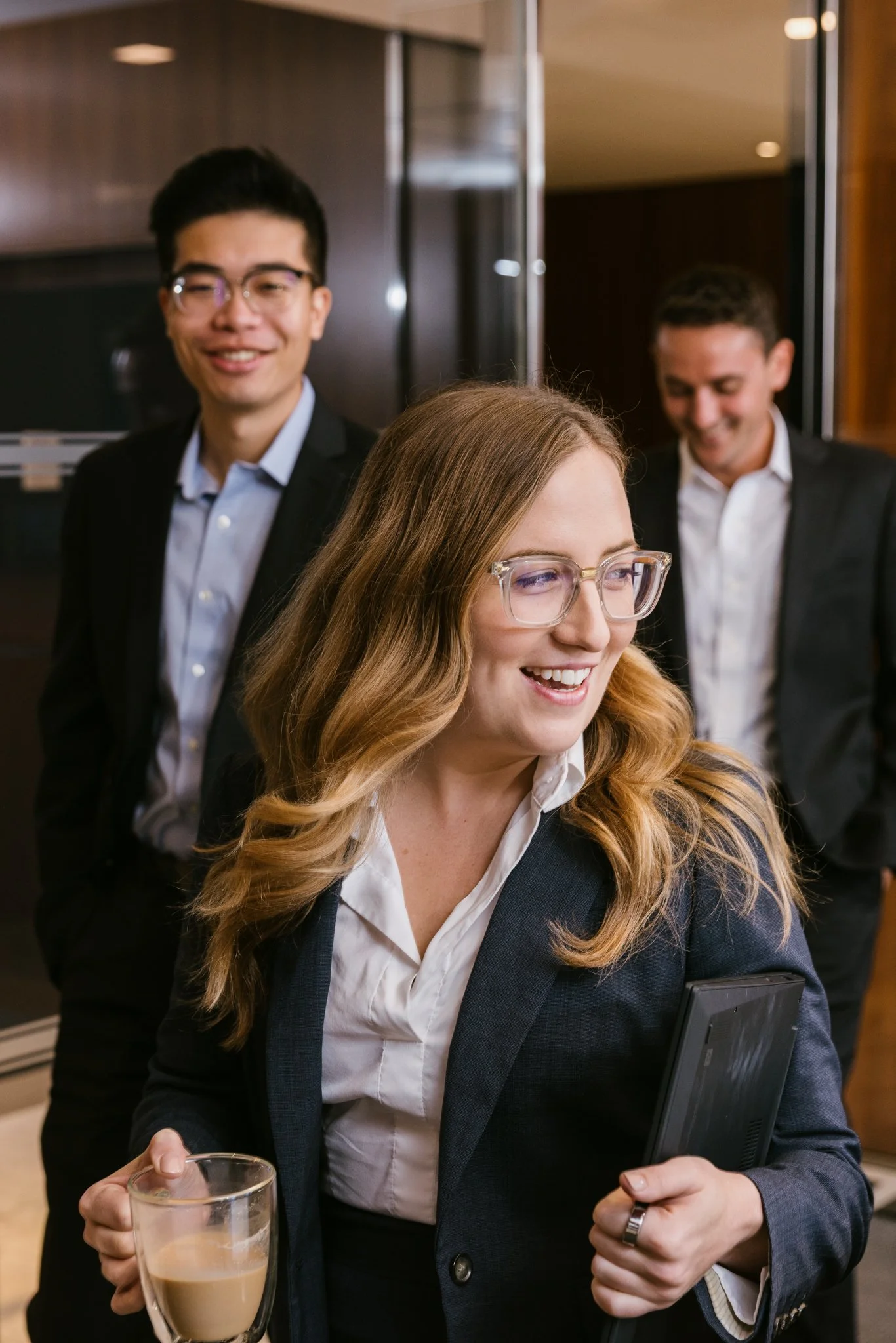 Work life brand photography by New York commercial photographer Adam Lerner - A business woman smiling walking into a business meeting in New York City