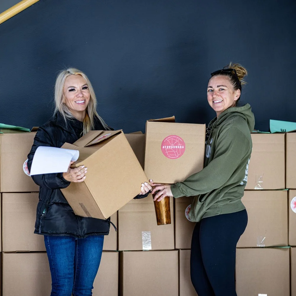 Two women smiling and posing with boxes of Hungry Jack mashed potatoes at an event.