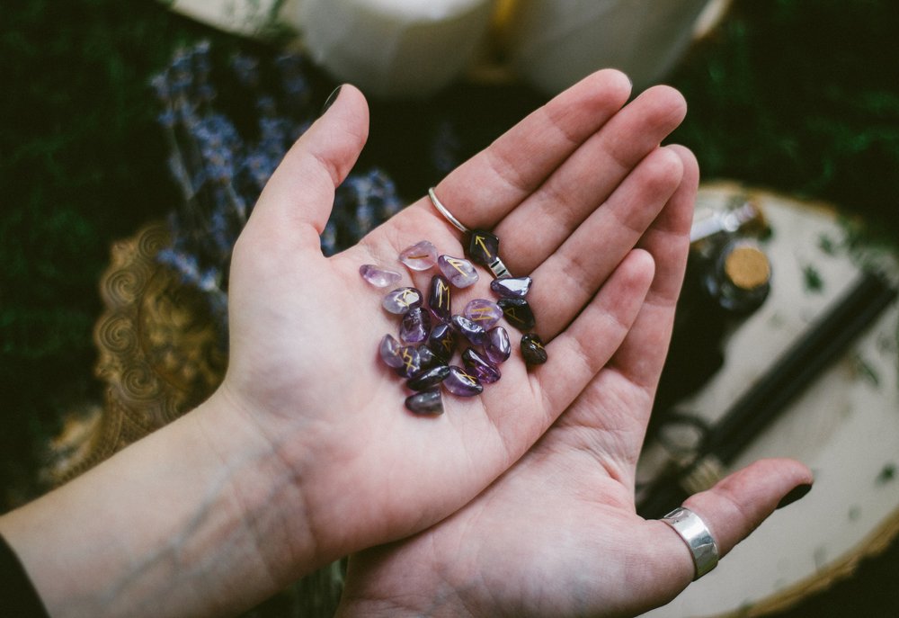 woman's hands holding a set of amethyst rune stones