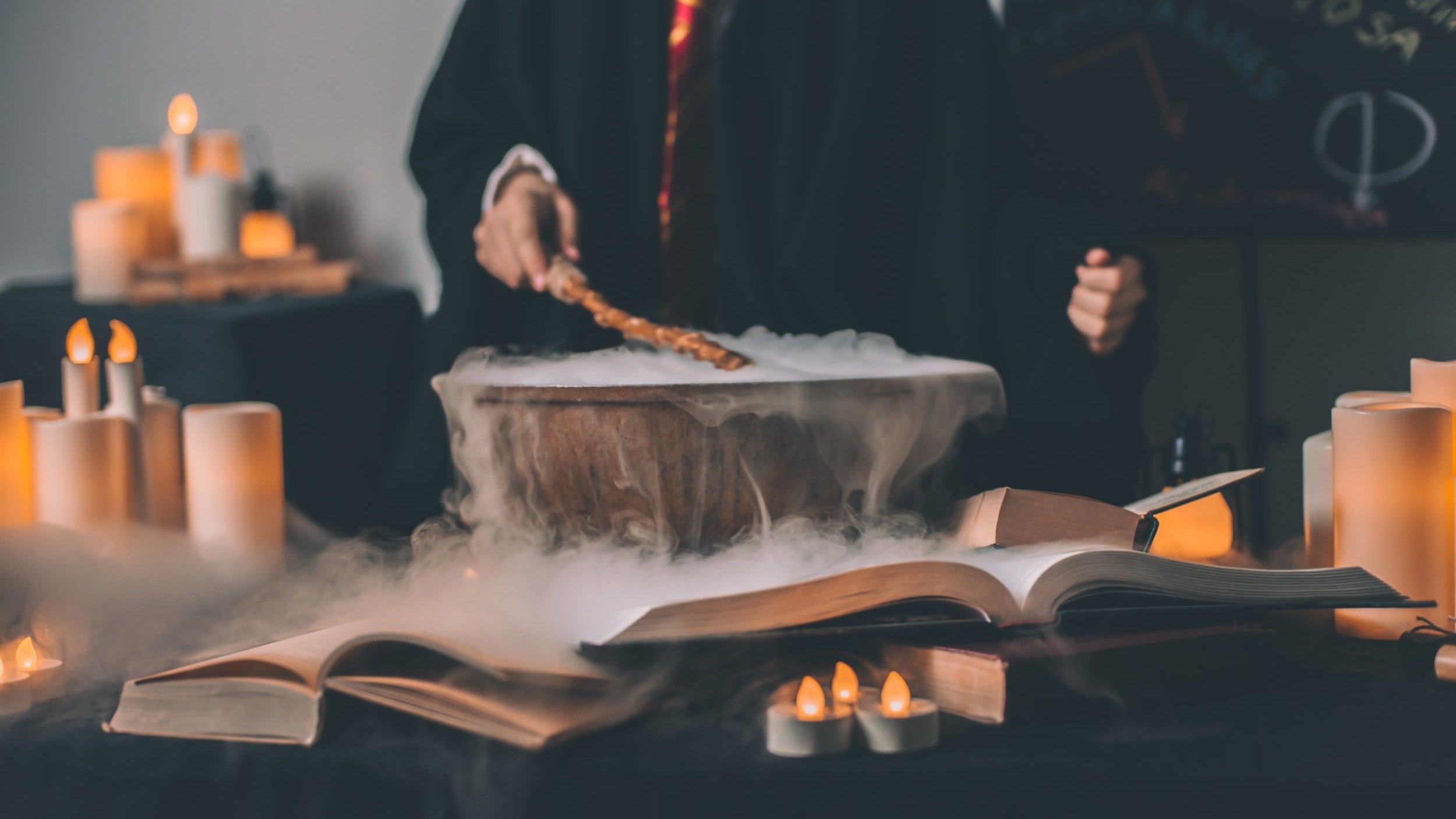 person in harry potter style clothing stirs a cauldron overflowing with fog next to a grimoire and surrounded by candles