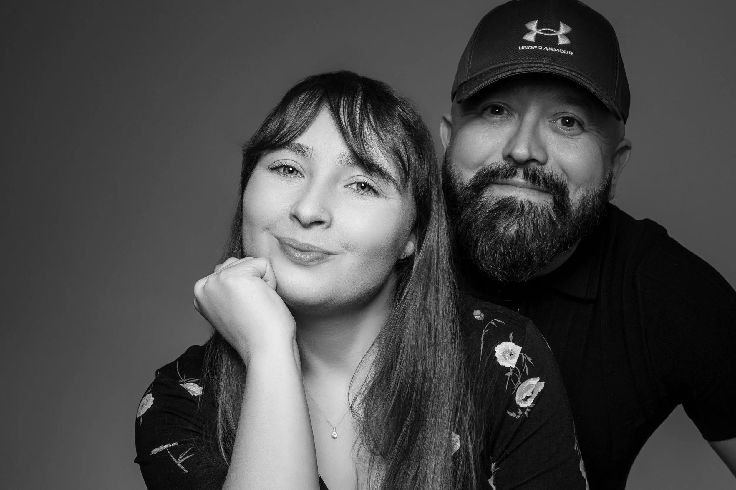 Black and white portrait of a woman with long hair and a man with a beard wearing a cap. Both are smiling and looking at the camera. Love. Growth. Rebuilding life. Soul mates. Finding each other. Marriage celebrated. Saved eachother.