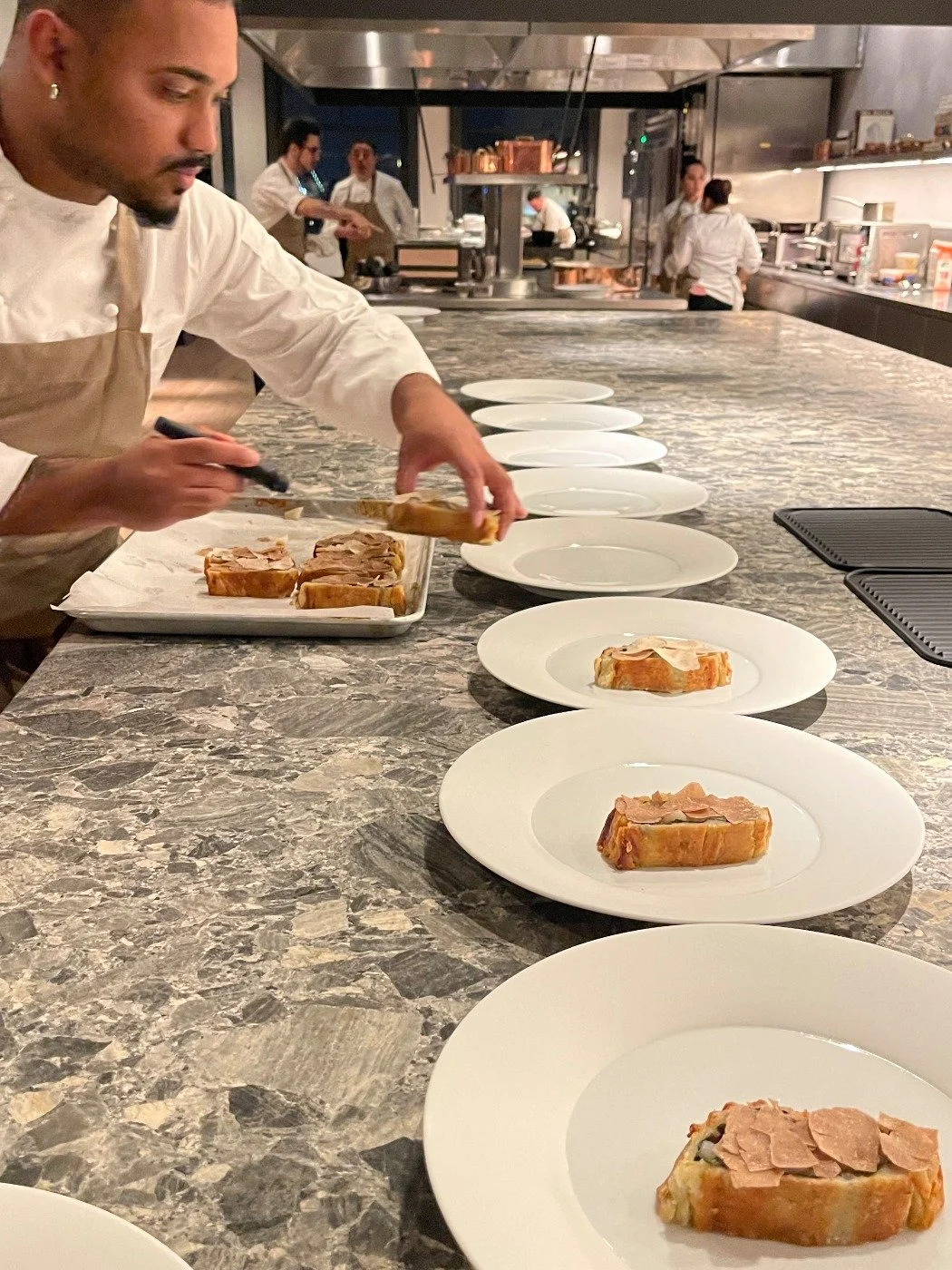 Cuisinier préparant des assiettes de terrine dans une cuisine de restaurant.