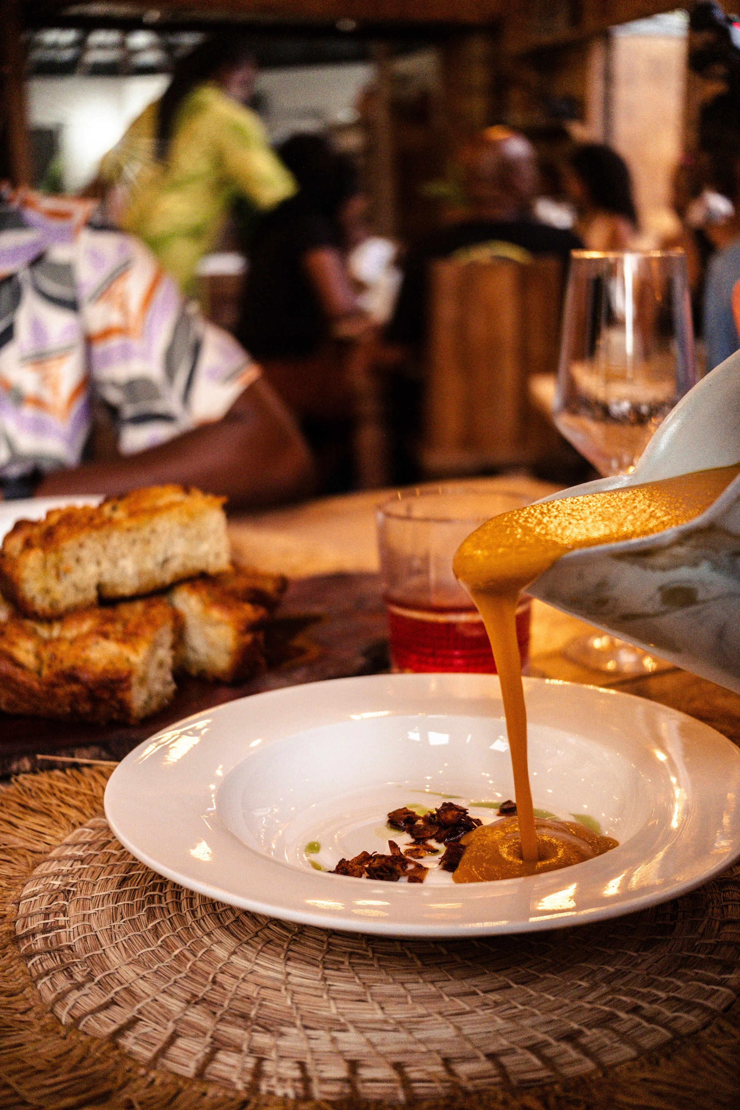 pouring pumpkin soup into a shallow white bowl