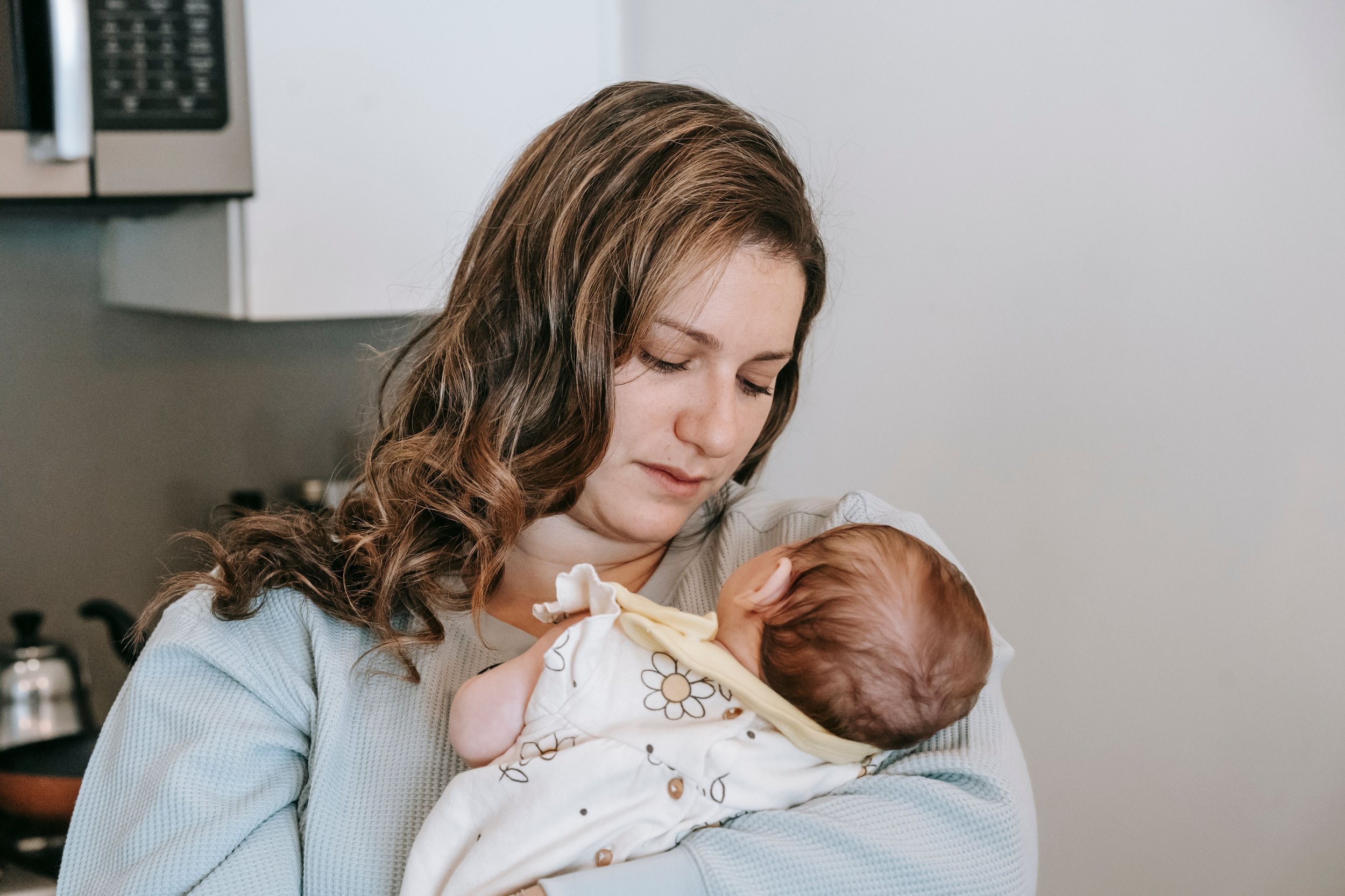 Woman recently gave birth looking at her child sadly, reflecting the weight of post partum anxiety. Image accompanying virtual therapy for clients in orange, los angeles county, san francisco