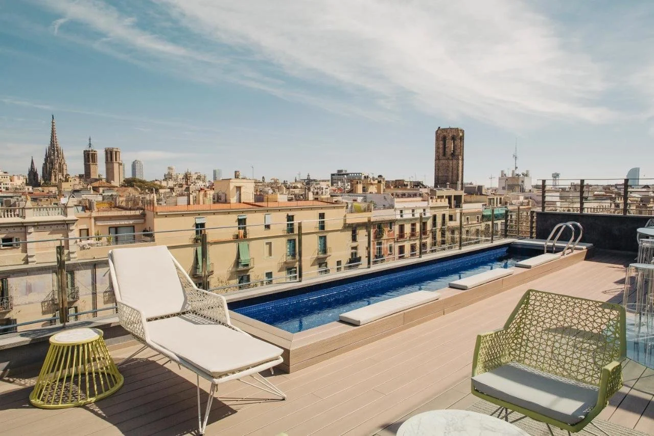 Hotel Bagués Barcelona rooftop infinity pool with Cathedral of Barcelona Gothic spires and W Barcelona sail tower in the city panorama