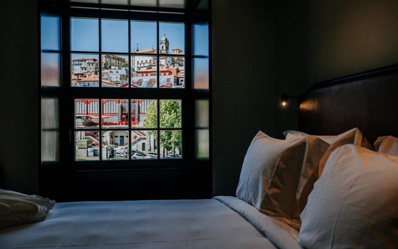 Exmo. Hotel by Olivia Porto hotel room with grid window view of Ferreira Borges Market and historic rooftops