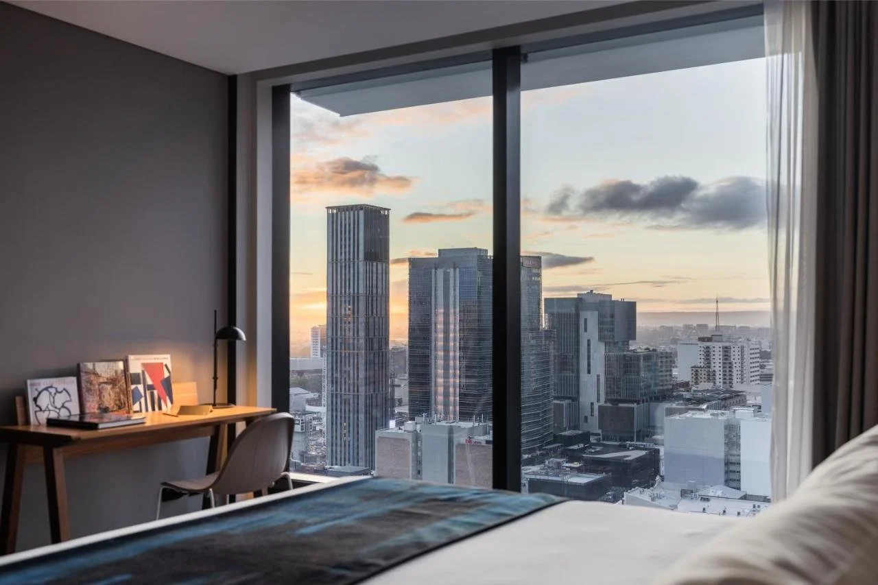 The Adnate Perth Art Series Perth room at sunset with floor-to-ceiling window and CBD tower skyline
