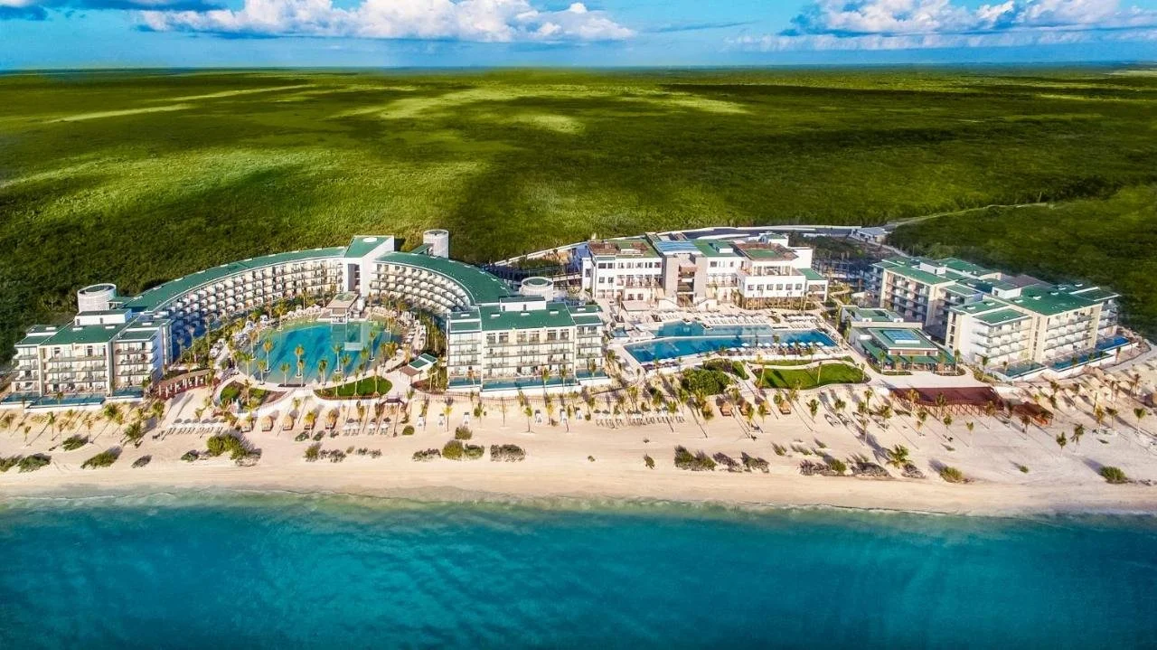 Haven Riviera Cancun aerial view of curved resort with pools and private white sand beach backed by Caribbean coast and mangroves