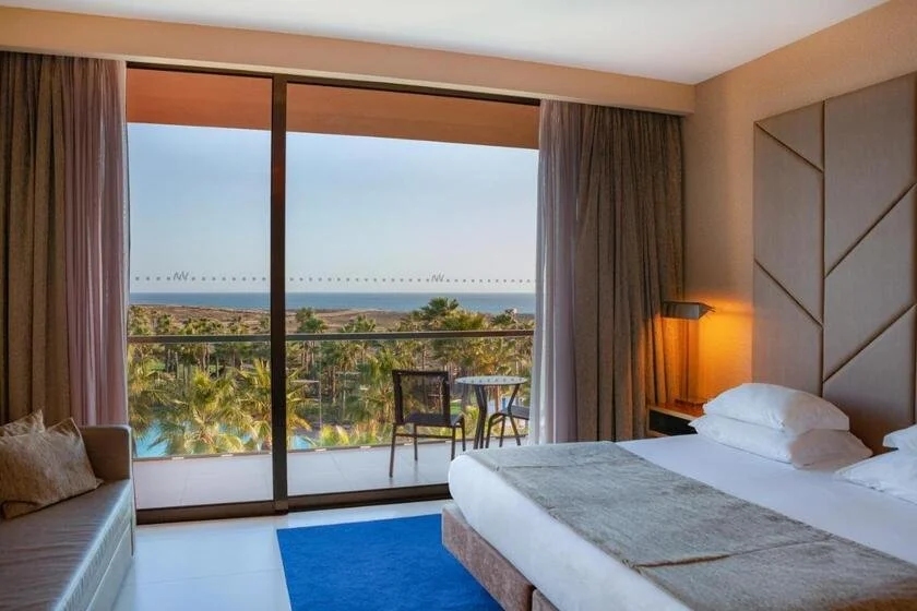 VidaMar Resort Hotel Algarve Albufeira hotel bedroom with balcony overlooking palm trees and Atlantic Ocean at dusk
