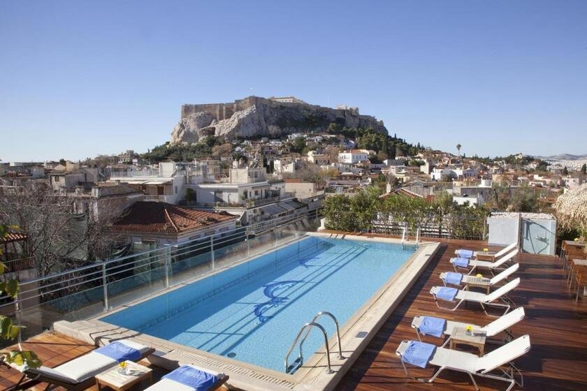 Electra Palace Athens rooftop pool with sun loungers on wooden deck and Acropolis rock rising directly above