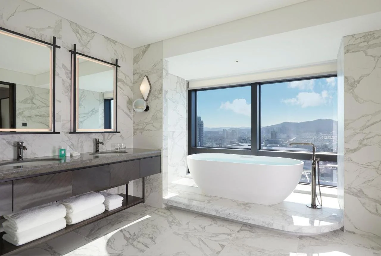 Grand InterContinental Seoul Parnas marble bathroom with freestanding bathtub and window overlooking Seoul skyline and mountains