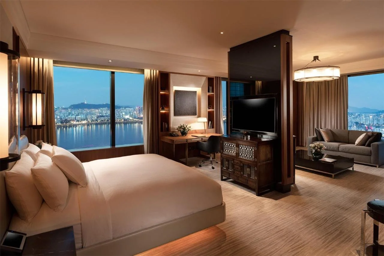 Conrad Seoul suite bedroom at night with Han River reflections and N Seoul Tower in panoramic city view