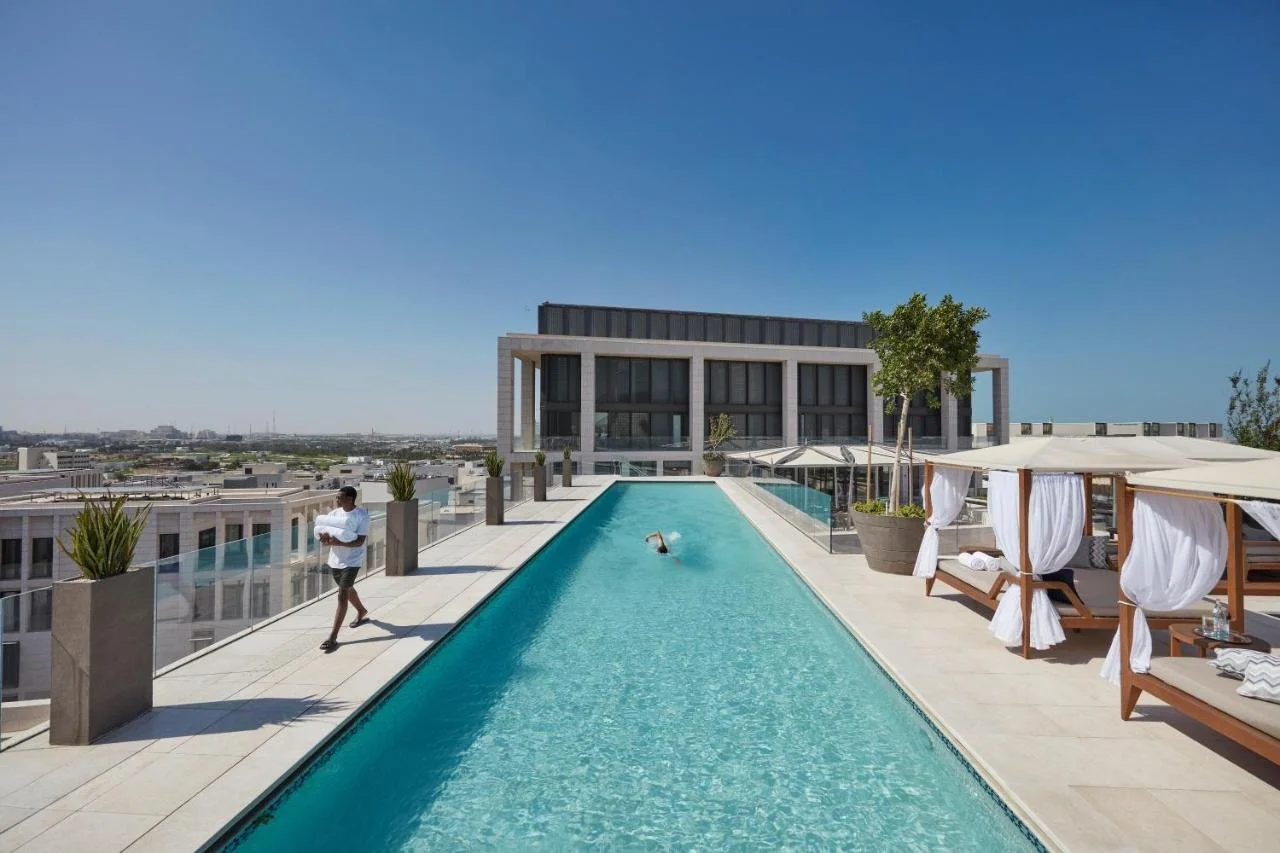 Mandarin Oriental Doha Doha rooftop lap pool with white cabana sun loungers and potted trees overlooking the low-rise Msheireb Downtown roofscape